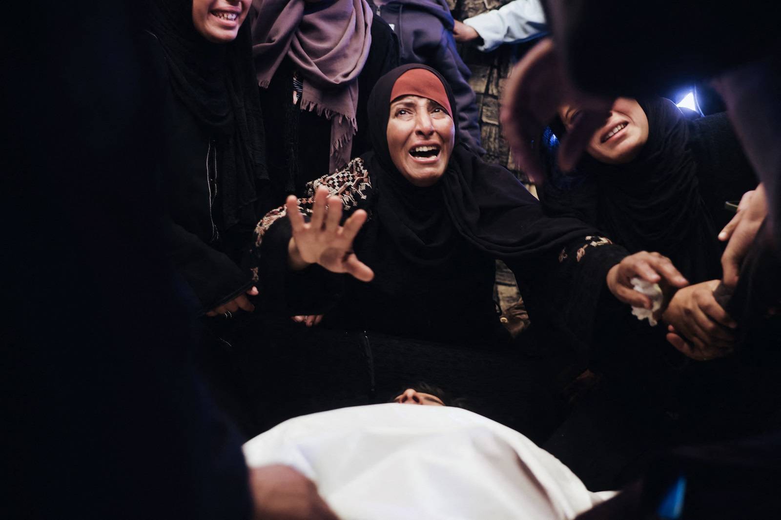 Filistinli bir kadın, Ramazan ayının ilk gününde Gazze Şeridi'nin güneyinde İsrail'in düzenlediği saldırıda hayatını kaybeden akrabasının yasını tutuyor (AFP)