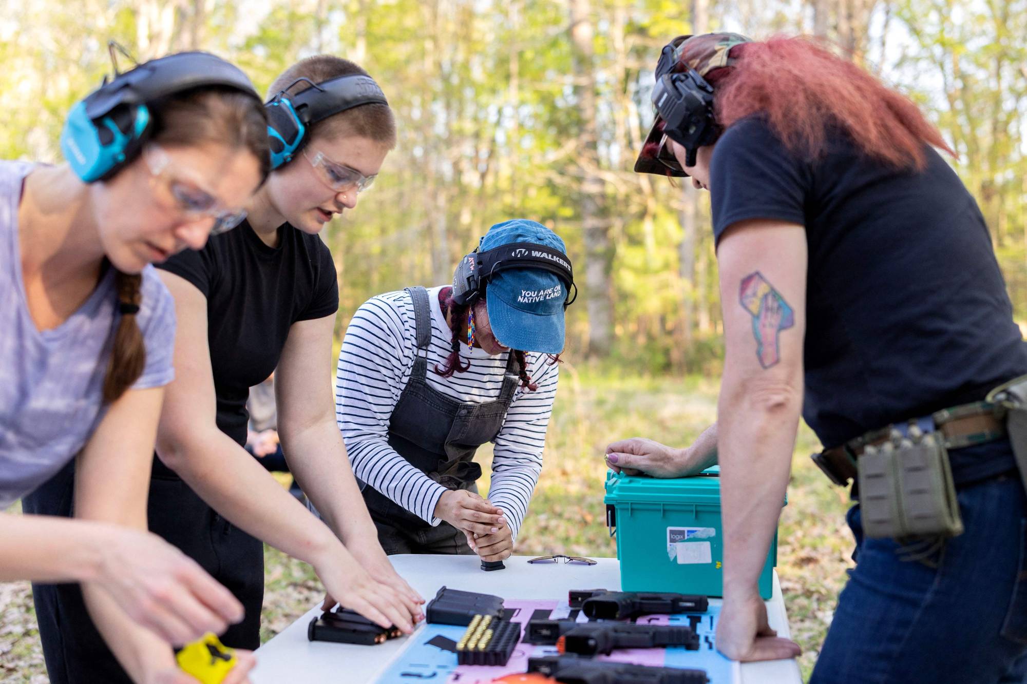 Eğitmen, kursiyerlere tabanca şarjörlerinin nasıl doldurulacağını açıklıyor (AFP).