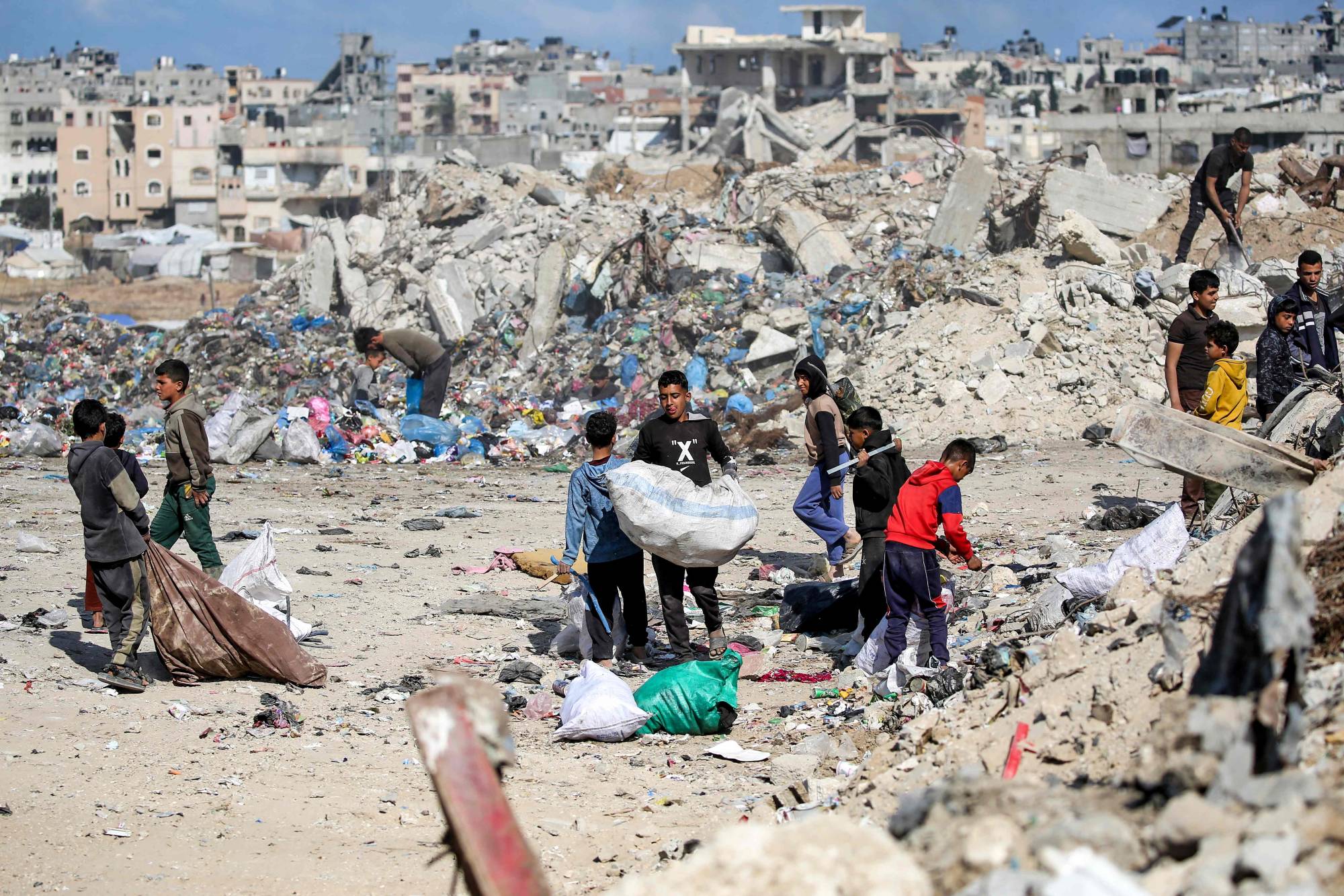 Gazze Şeridi’nin orta kesimindeki Nuseyrat Mülteci Kampı’nda çöp yığınları arasında işe yarar malzeme arayan Filistinli çocuklar, 7 Mayıs 2026 (AFP)
