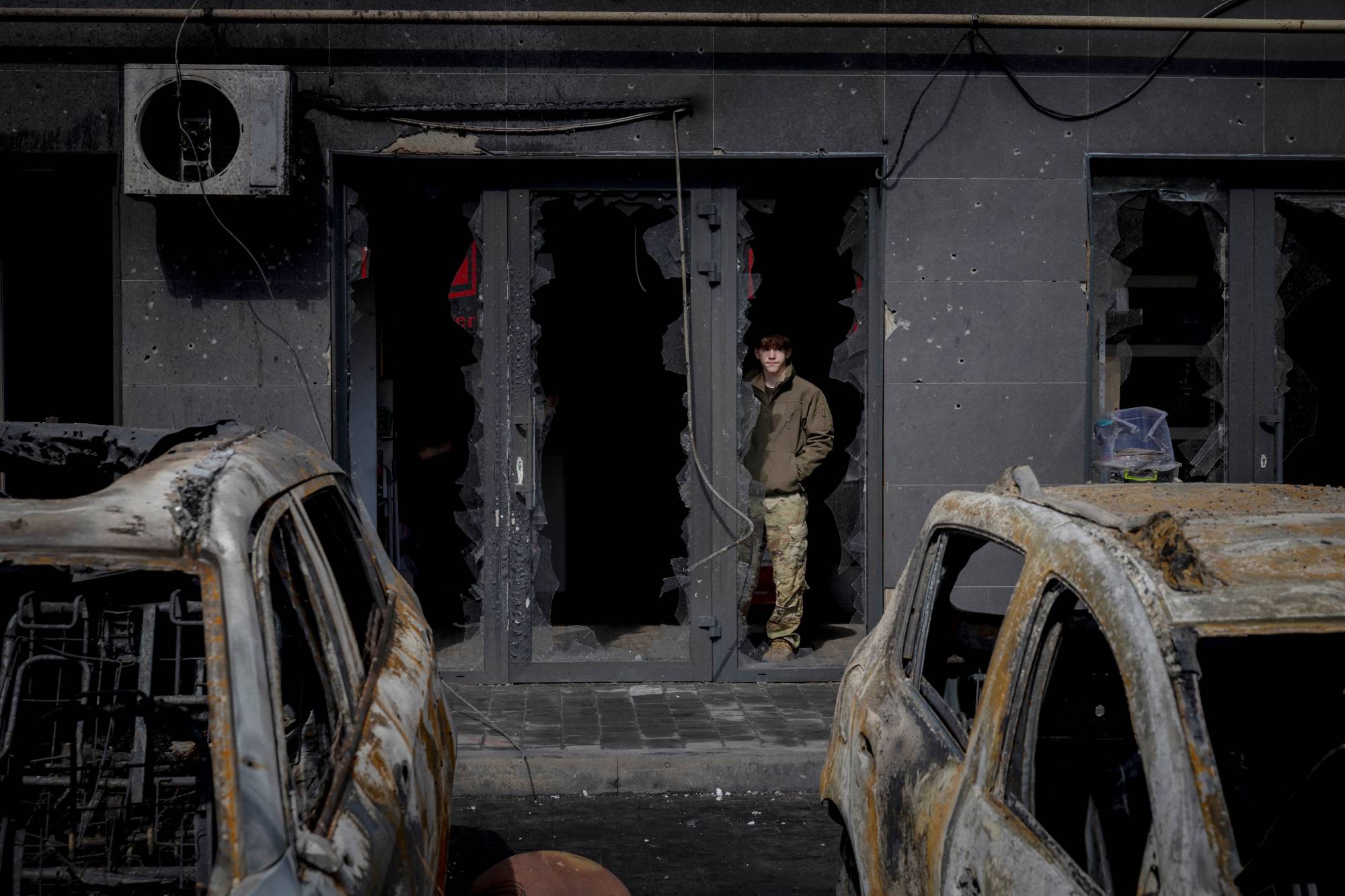 Kiev yakınlarındaki bir yerleşim kompleksinde Rusya'nın füze ve insansız hava aracı saldırısının ardından yanmış araçların yanında duran bir adam (Reuters)