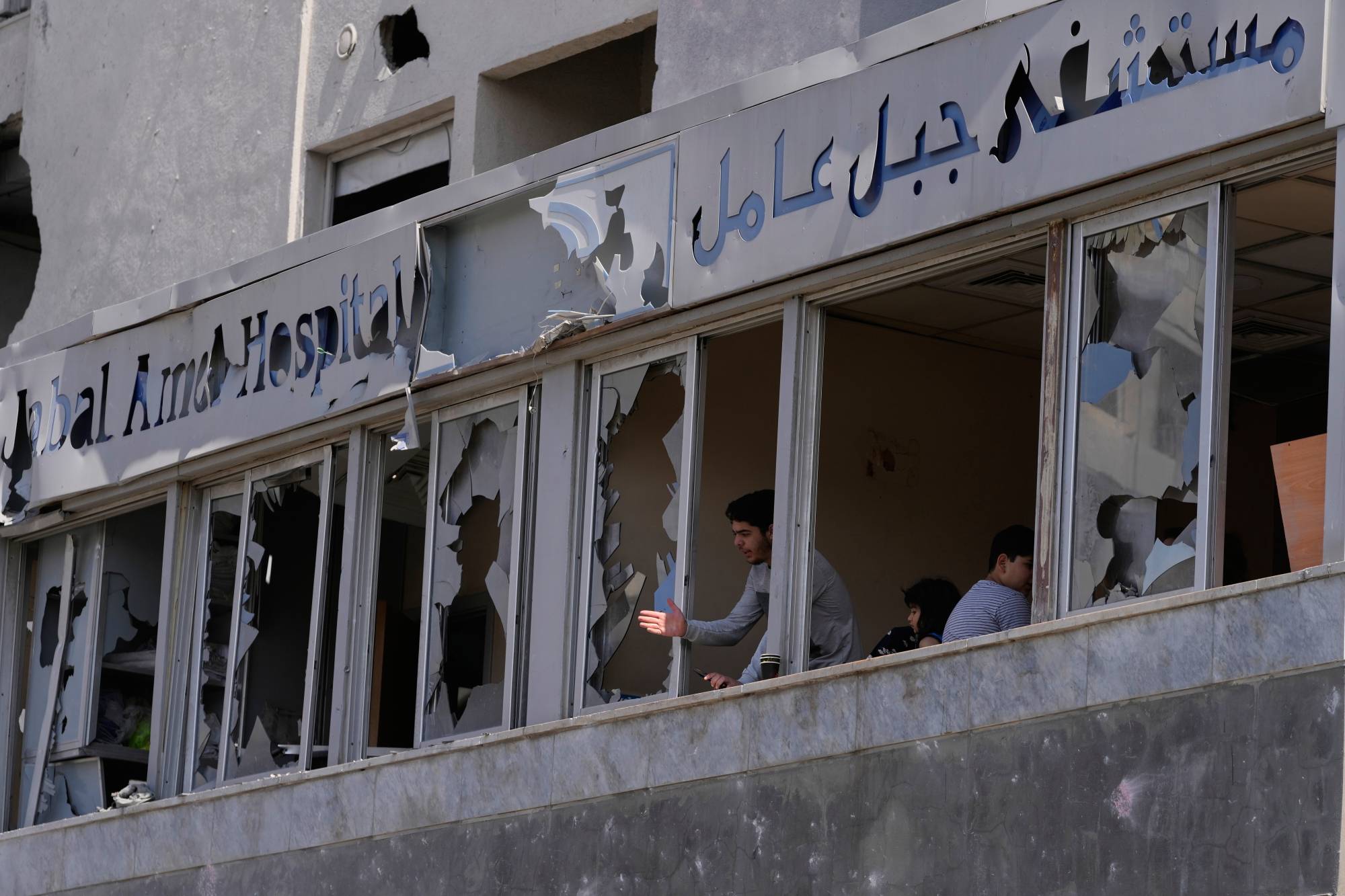 İsrail'in yakındaki bir binayı hedef alan hava saldırısı sonucu hasar gören Lübnan'ın güneyinde Sur kentindeki Cebel Emel Hastanesi'nde kırık pencerelerden hasarı inceleyen bir kişi, (AP)