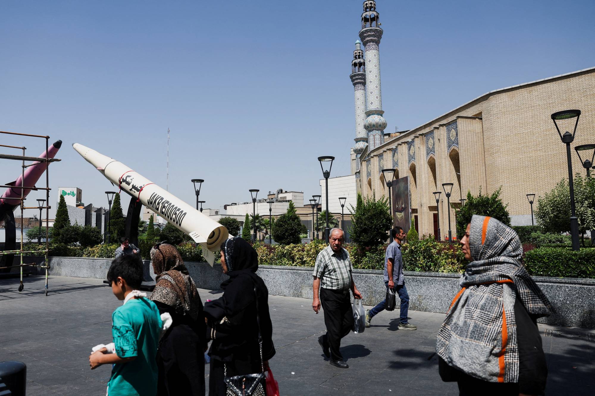 Tahran'da bir sokakta, İran füzesinin sembolik bir modelinin önünden geçen insanlar görülüyor, (Reuters)