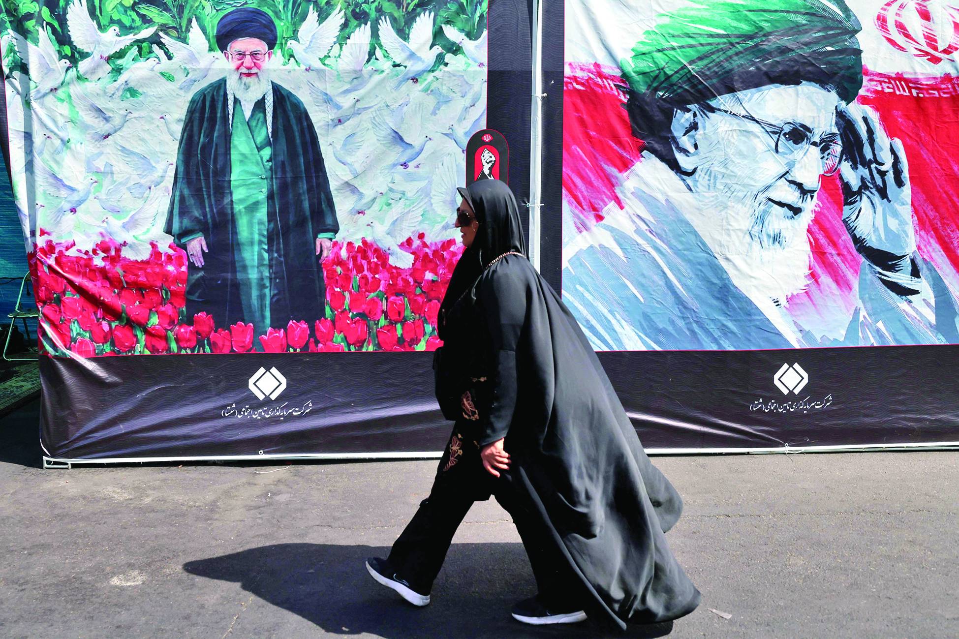 Bir kadın, dün Tahran'da İran'ın dini lideri Ali Hamaney'in fotoğrafının yer aldığı bir reklam panosunun önünden geçiyor. (AFP)