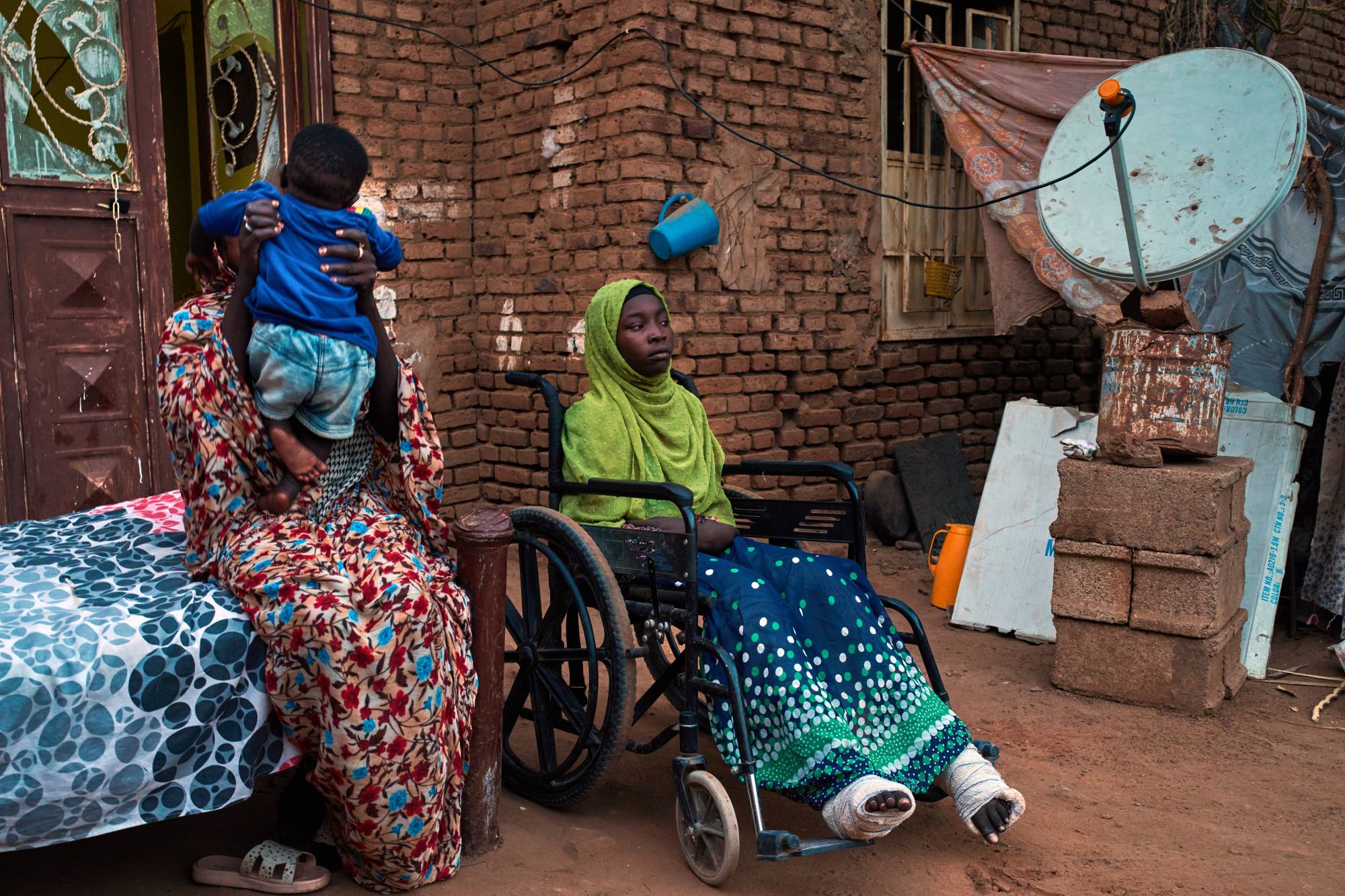  Nisan ayında Hartum'daki evinin avlusunda, bombalı saldırıda yaralanan Sudanlı bir kız çocuğu tekerlekli sandalyesinde oturuyor (AP)