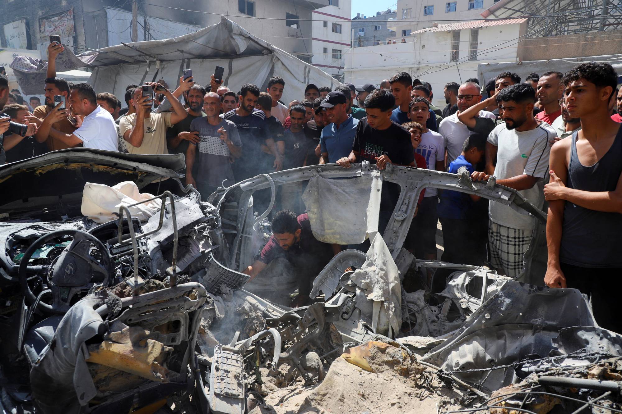 İsrail saldırısında hedef alınan bir aracı inceleyen Filistinliler, Gazze, 9 Temmuz 2026 (Reuters)