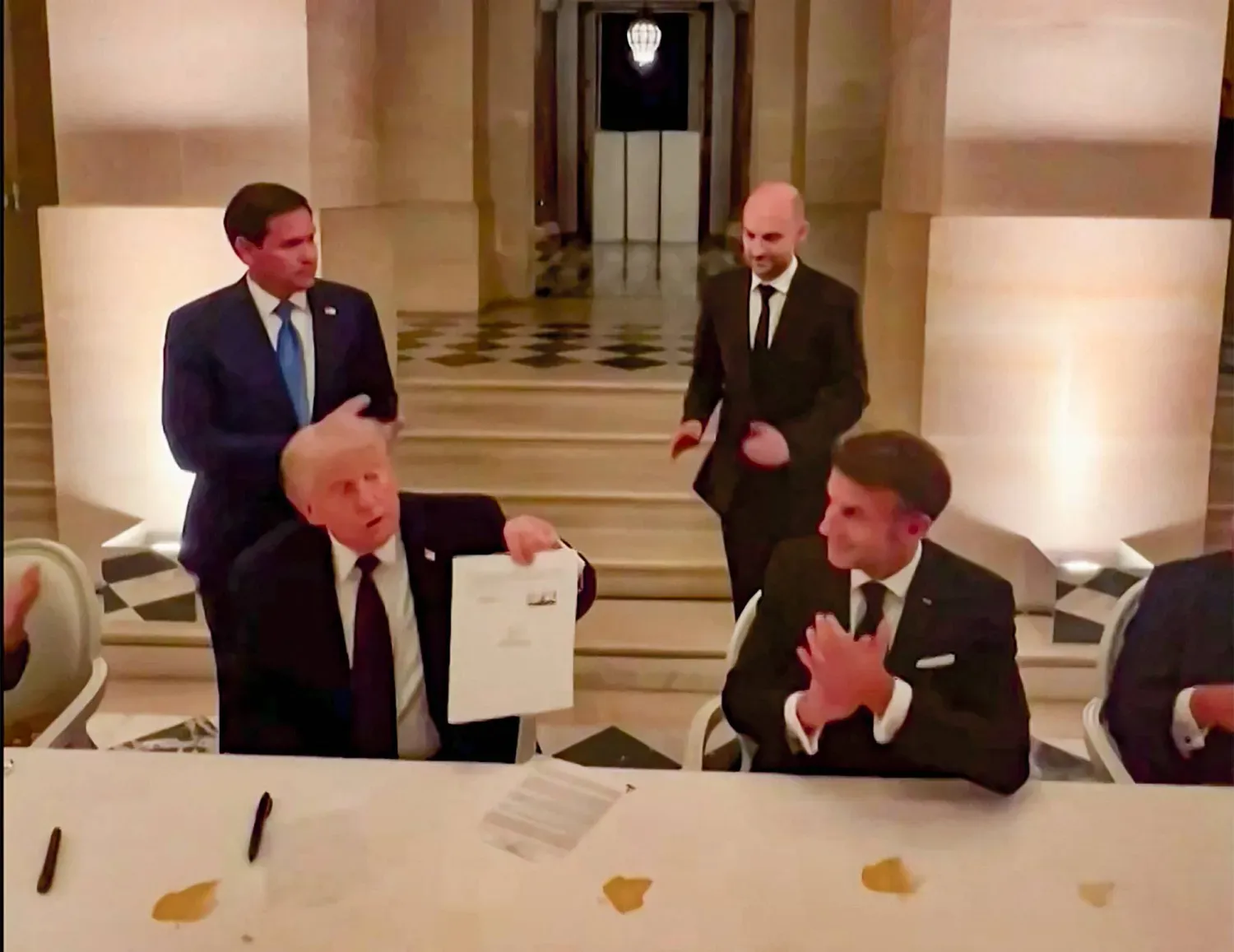 ABD Başkanı Donald Trump, 18 Haziran akşamı Versay Sarayı’nda İran ile varılan çerçeve anlaşması belgesini imzaladıktan sonra elinde tutarken (AFP)