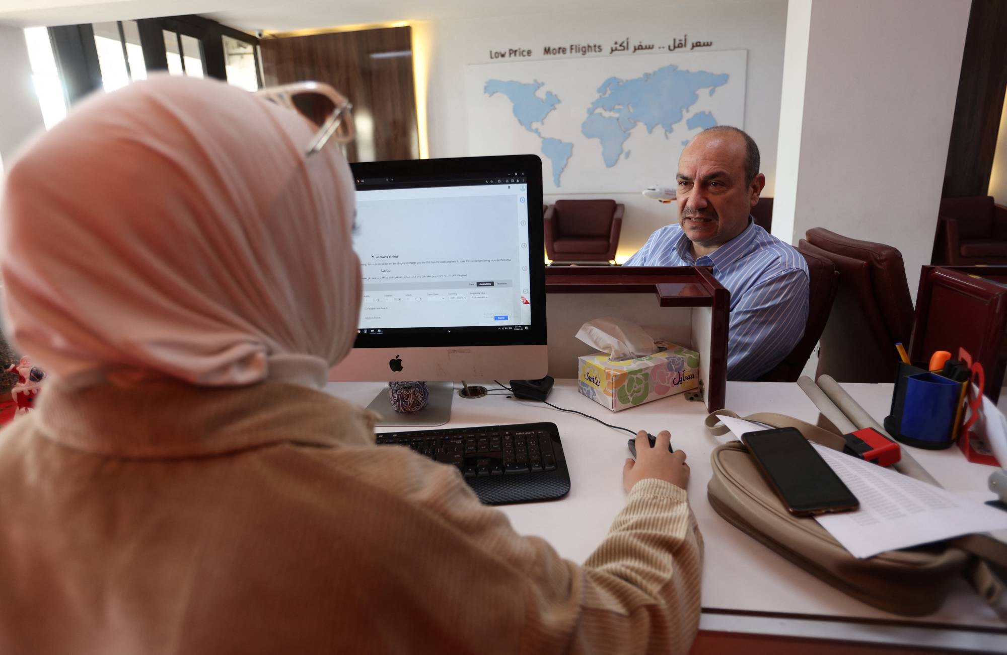 23 Ocak 2024'te Bağdat'taki Fly Baghdad ofisinde bir müşteri bir çalışanla konuşuyor (Reuters).