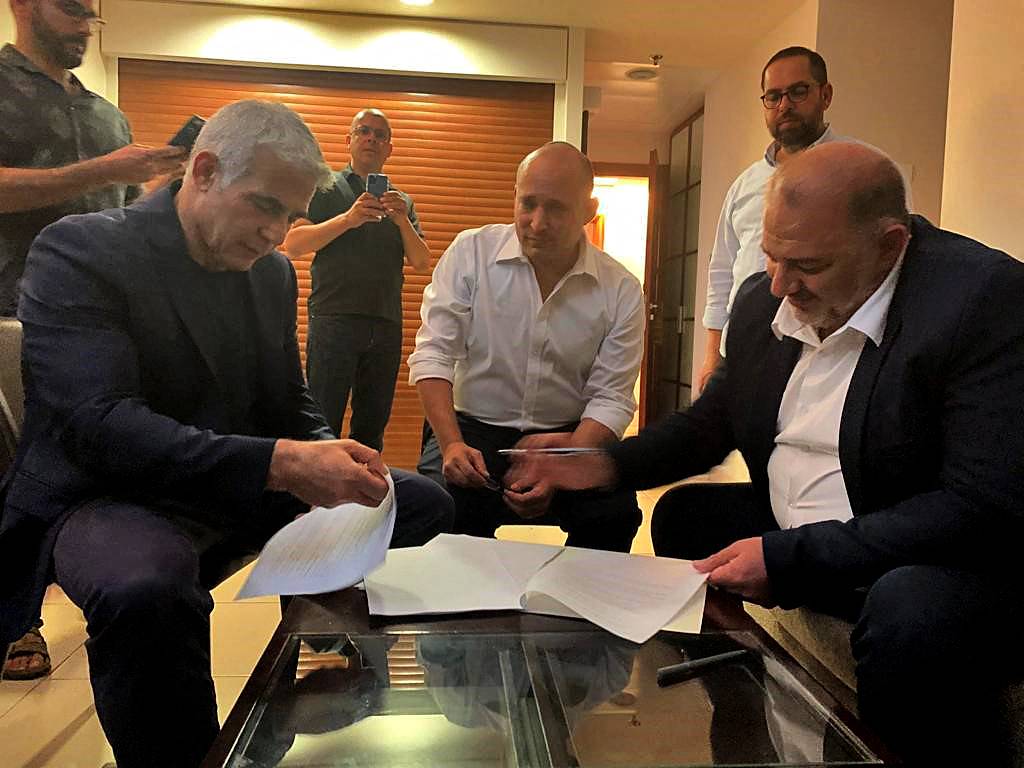 Birleşik Arap Listesi lideri Mansur Abbas (sağda), Tel Aviv’de Yair Lapid (solda) ve Naftali Bennett ile hükümet koalisyonu anlaşmasını imzalarken, Haziran 2021 (AFP)