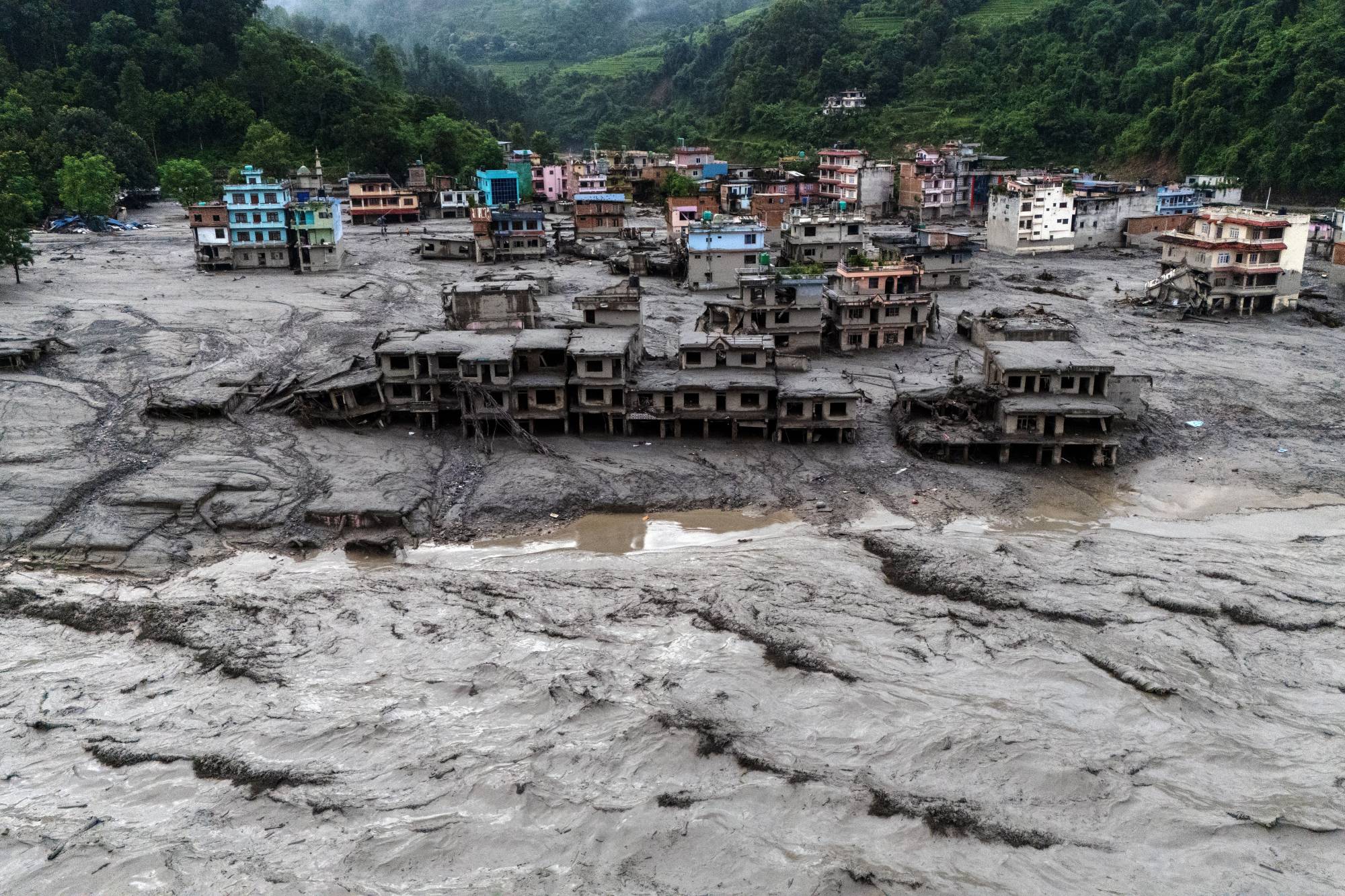Nepal’in Nuwakot bölgesindeki Devighat’ta, ani seller ve ölümcül toprak kaymalarının ardından Likhhu Nehri kıyısında çamurla kaplanan hasarlı binalar ve evler. (Reuters)