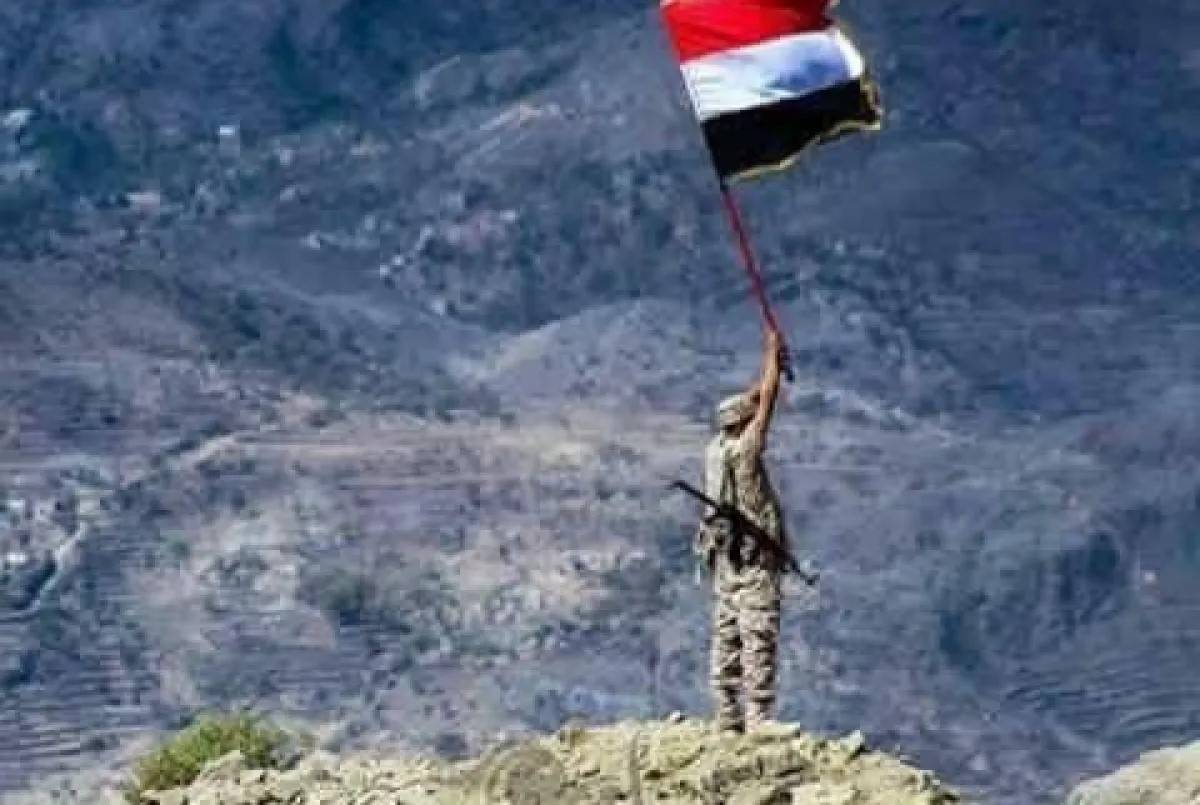 Yemen ordusundan bir asker, ele geçirilen mevzilerden birinde bayrak kaldırıyor. (Askerî medya)