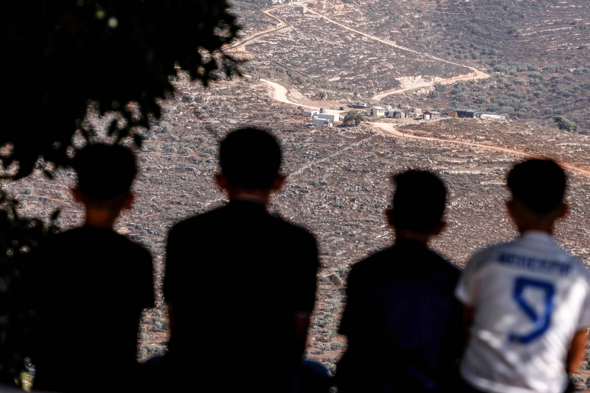 Filistinli gençler, pazartesi günü Batı Şeria’daki Filistin köyü Osrin’in karşısında bulunan İsrail yerleşim karakoluna bakıyor. (AFP)