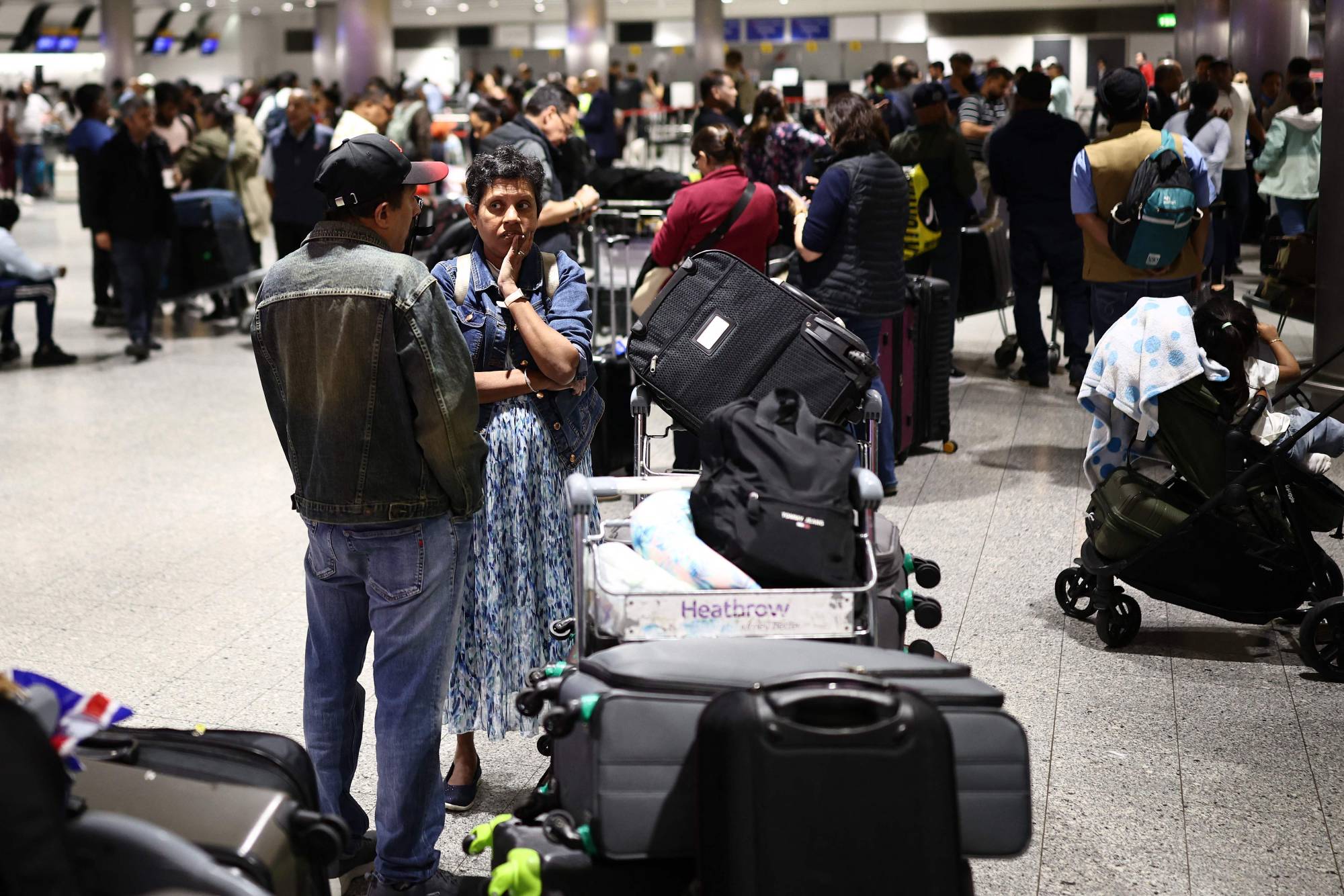  Uçuşları geciken yolcular, Heathrow Havalimanı’nın 3 numaralı terminalinde bekliyor. (AFP)