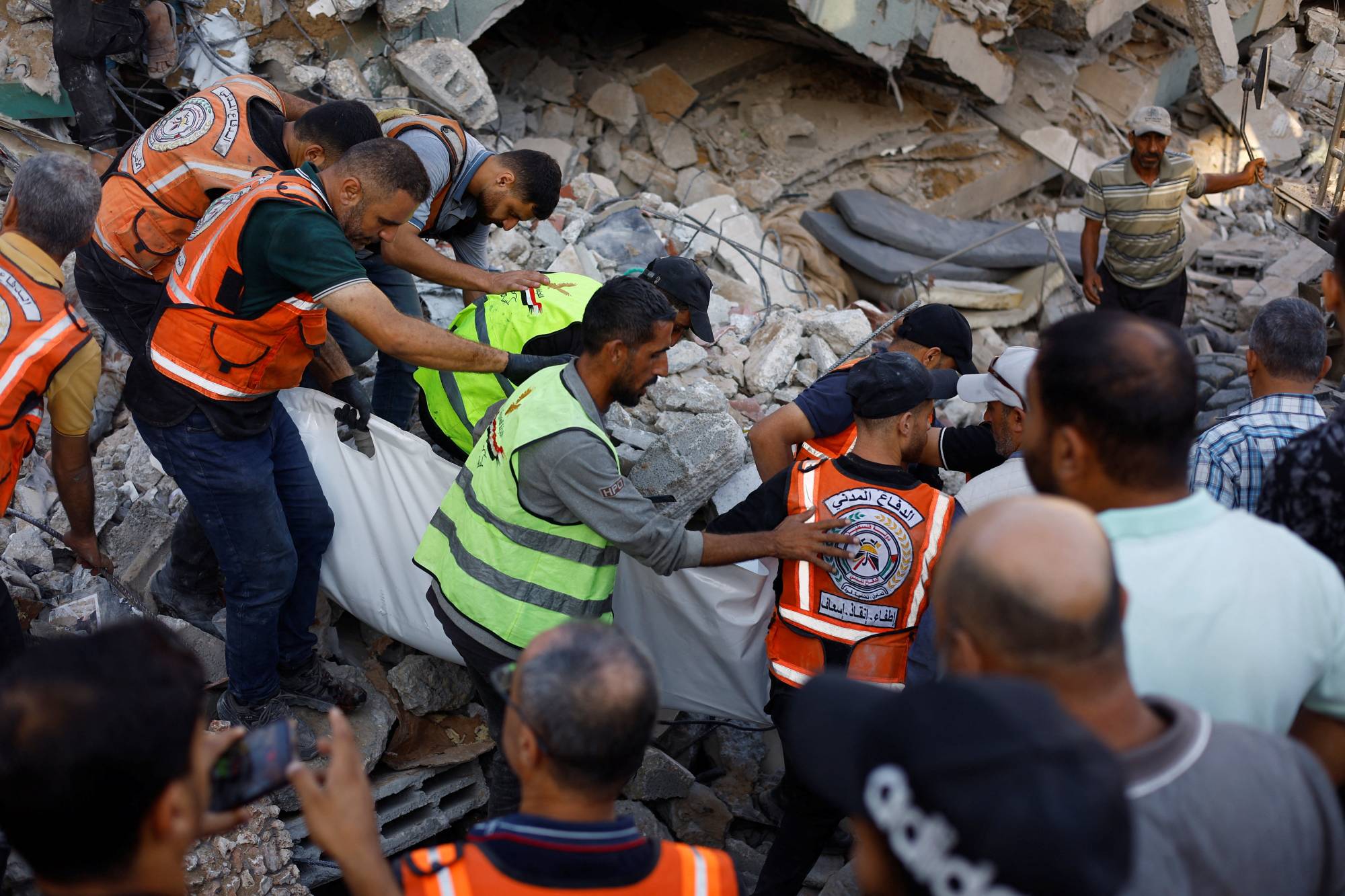 Sivil Savunma ekipleri, bugün Gazze Şehri'nde bir binanın çökmesi sonucu hayatını kaybeden bir kişinin cenazesini taşıyor (Reuters)