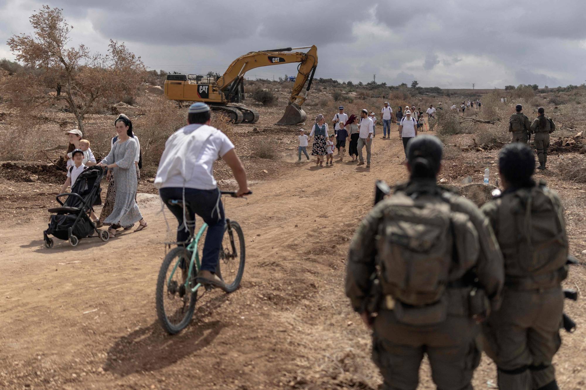 İsrailli aileler, işgal altındaki Batı Şeria’da bugün Cenin kenti yakınlarında, Ganim ve Kadim yerleşimleri arasındaki yolda düzenlenen yürüyüşe katılıyor. (AFP)