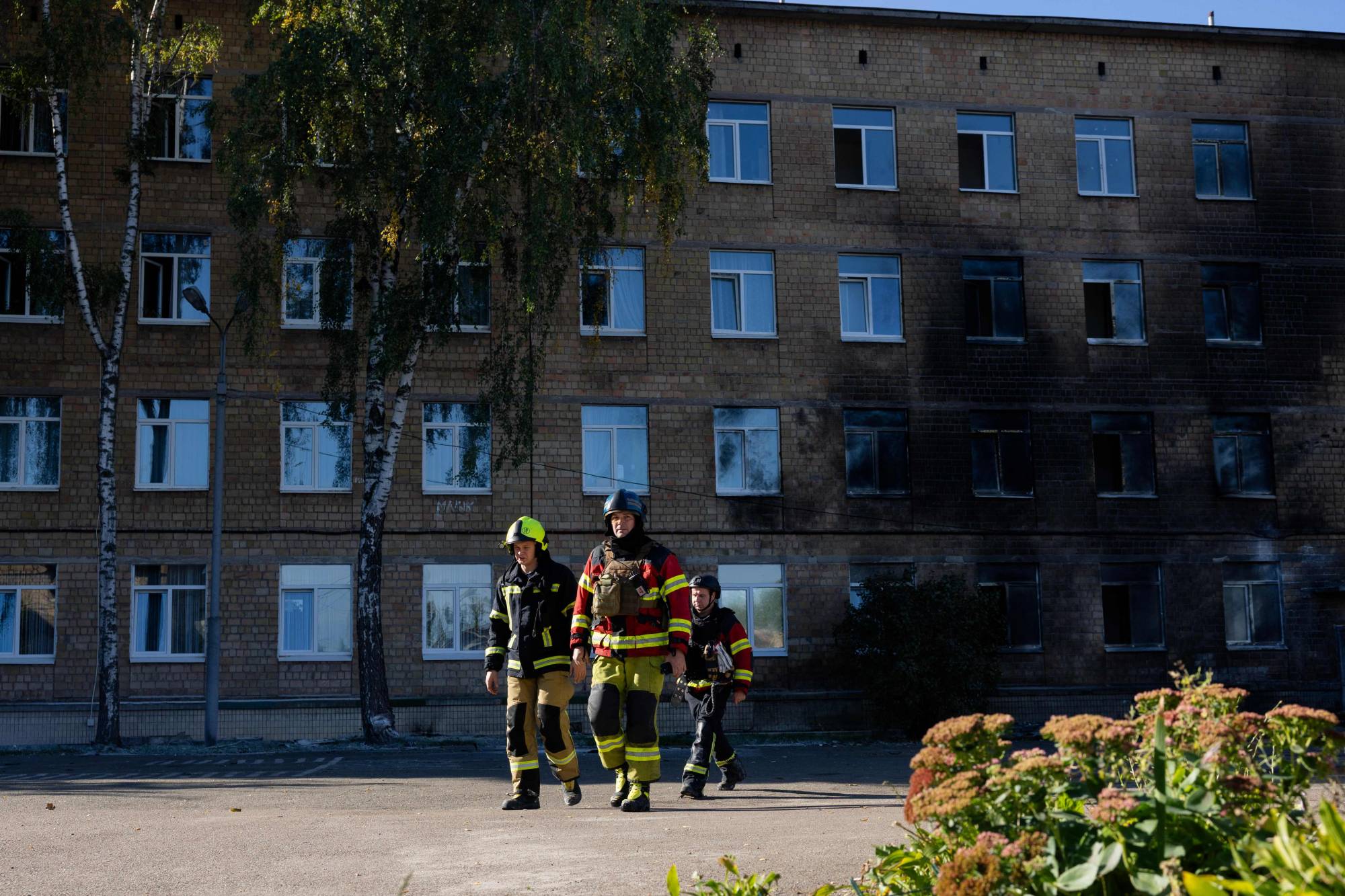  Kiev'de bombardımanda hasar gören bir okulun önünde kurtarma ekipleri... Ukrayna savaşında gerçek nerede? (AFP)