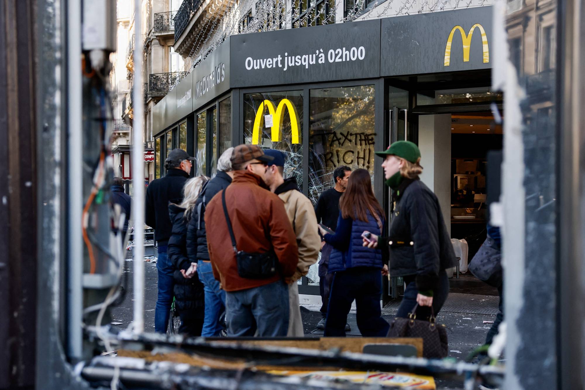 Paris’te hayat pahalılığı ve artan akaryakıt fiyatlarını protesto etmek amacıyla düzenlenen ulusal gösteri gününde yaşanan çatışmaların ertesi günü, vatandaşlar McDonald's şubesinin hasar gören pencerelerinin önünde beklerken, (Reuters)