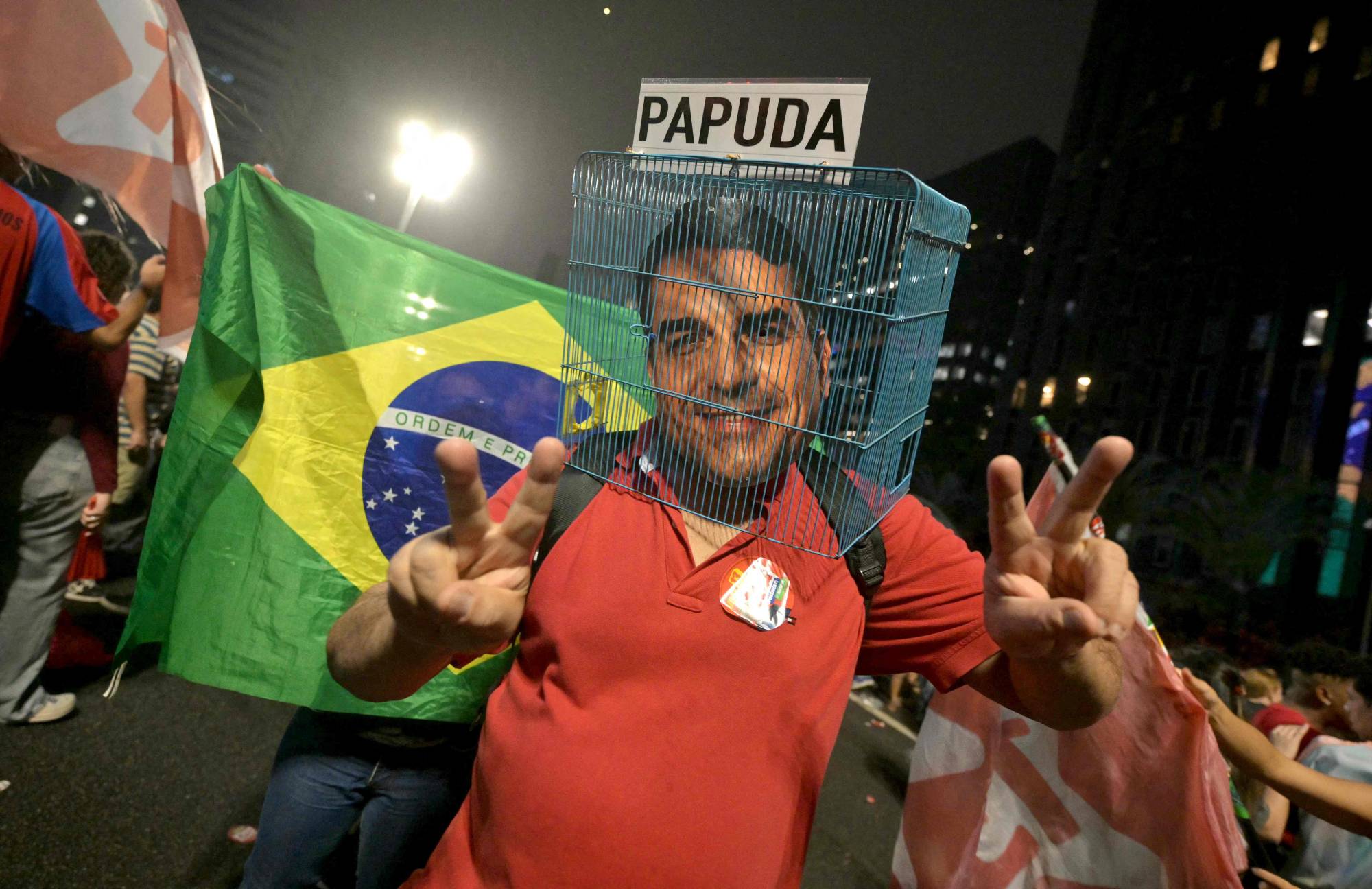 Brezilyalı bir Lula destekçisi, Sao Paulo’daki seçim zaferi kutlamaları sırasında yenilgiye uğrayan sağcı aday Flavio Bolsonaro’nun maskesini bir kafesin içine yerleştirdi. (AFP)