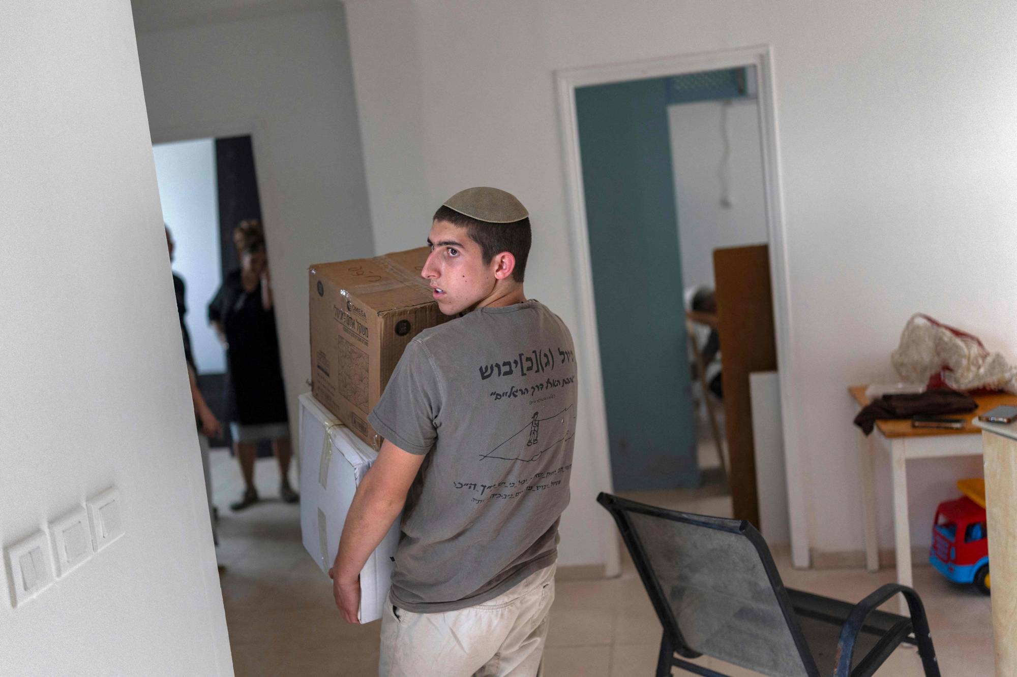 İsrail işgali altındaki Batı Şeria’da, Filistinlilerin Salem köyü yakınlarındaki yeni Şalem yerleşiminin açılışı sırasında bir İsrailli yerleşimci, kutuları bir eve taşıyor. (AFP)