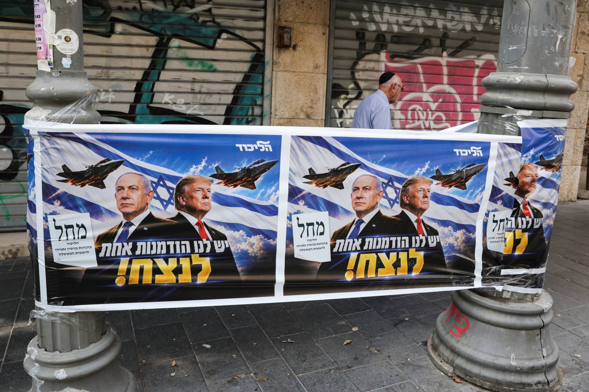 İsrail Başbakanı ve Likud Partisi lideri Binyamin Netanyahu ile ABD Başkanı Donald Trump’ın yer aldığı bir afişin önünden geçen bir kişi, Kudüs, (Reuters)