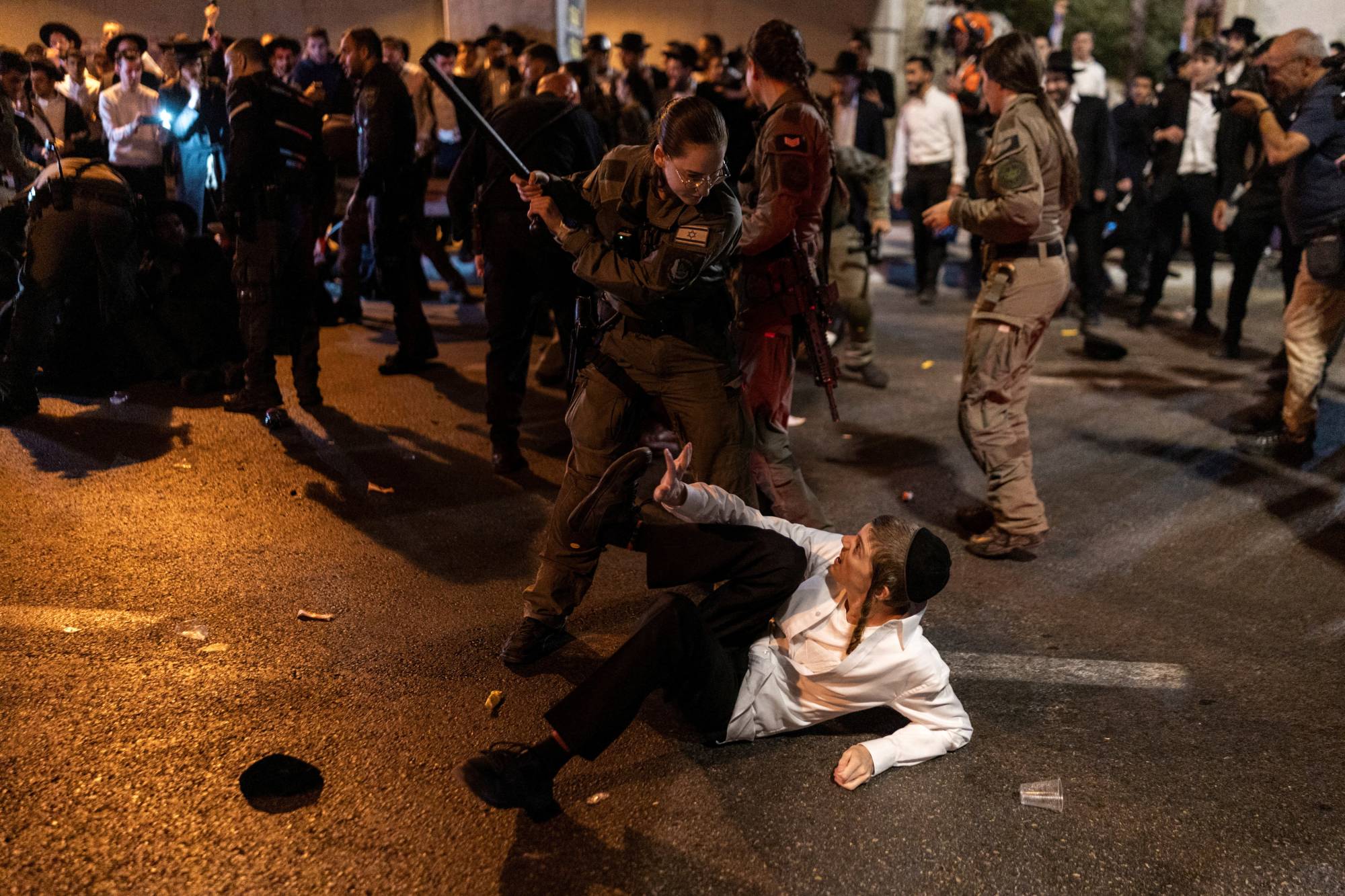 İsrail güvenlik güçlerine mensup bir görevli, 29 Ekim 2026’da Bnei Brak kentinde Ultra-Ortodoks Yahudilerin askere alınmasına karşı düzenlenen protesto sırasında cop taşıyarak bir Haredi göstericiyi yoldan uzaklaştırmaya çalışıyor. (Reuters)