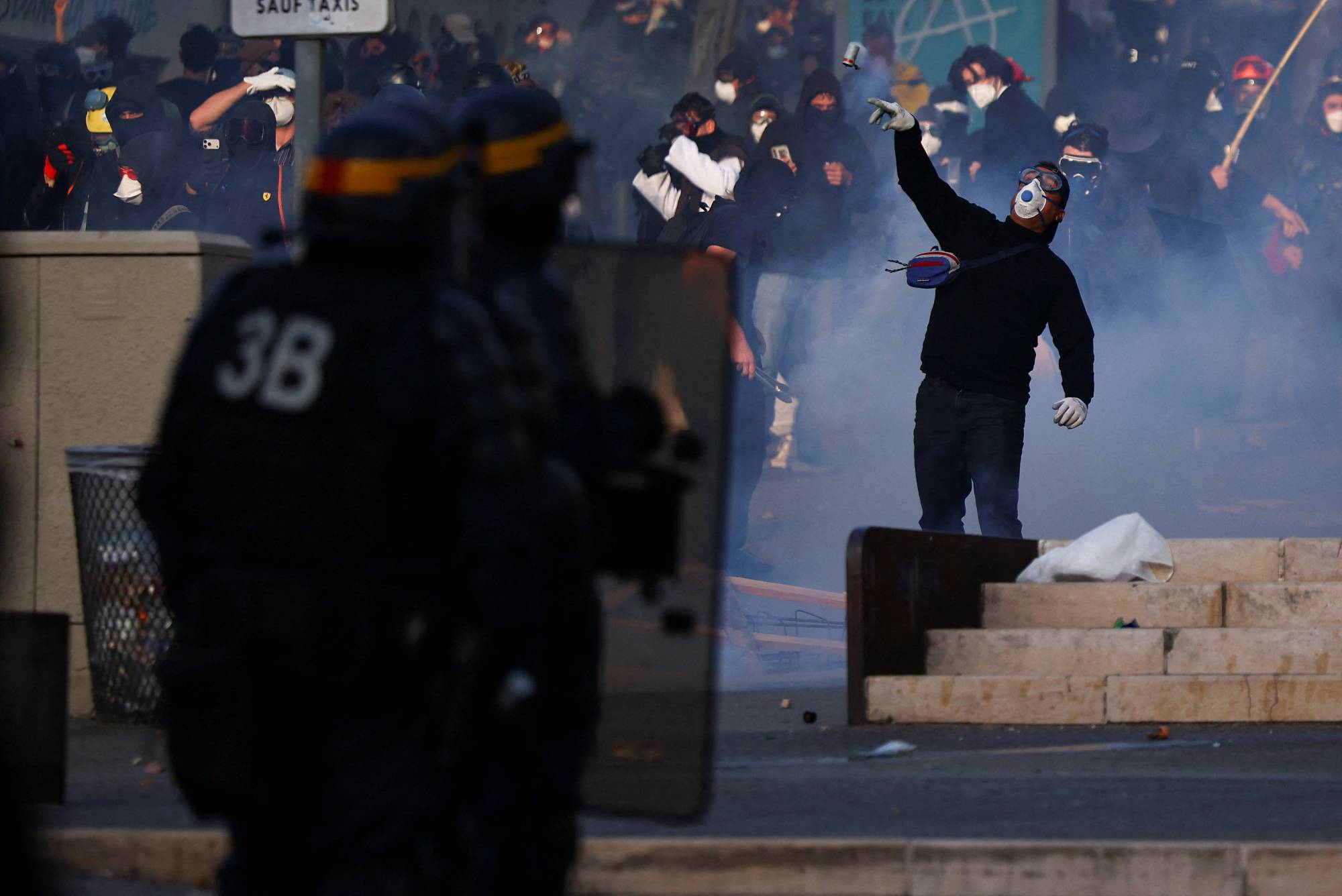Marsilya’da bir gösterici, polislere doğru göz yaşartıcı gaz bombası atıyor. (Reuters)