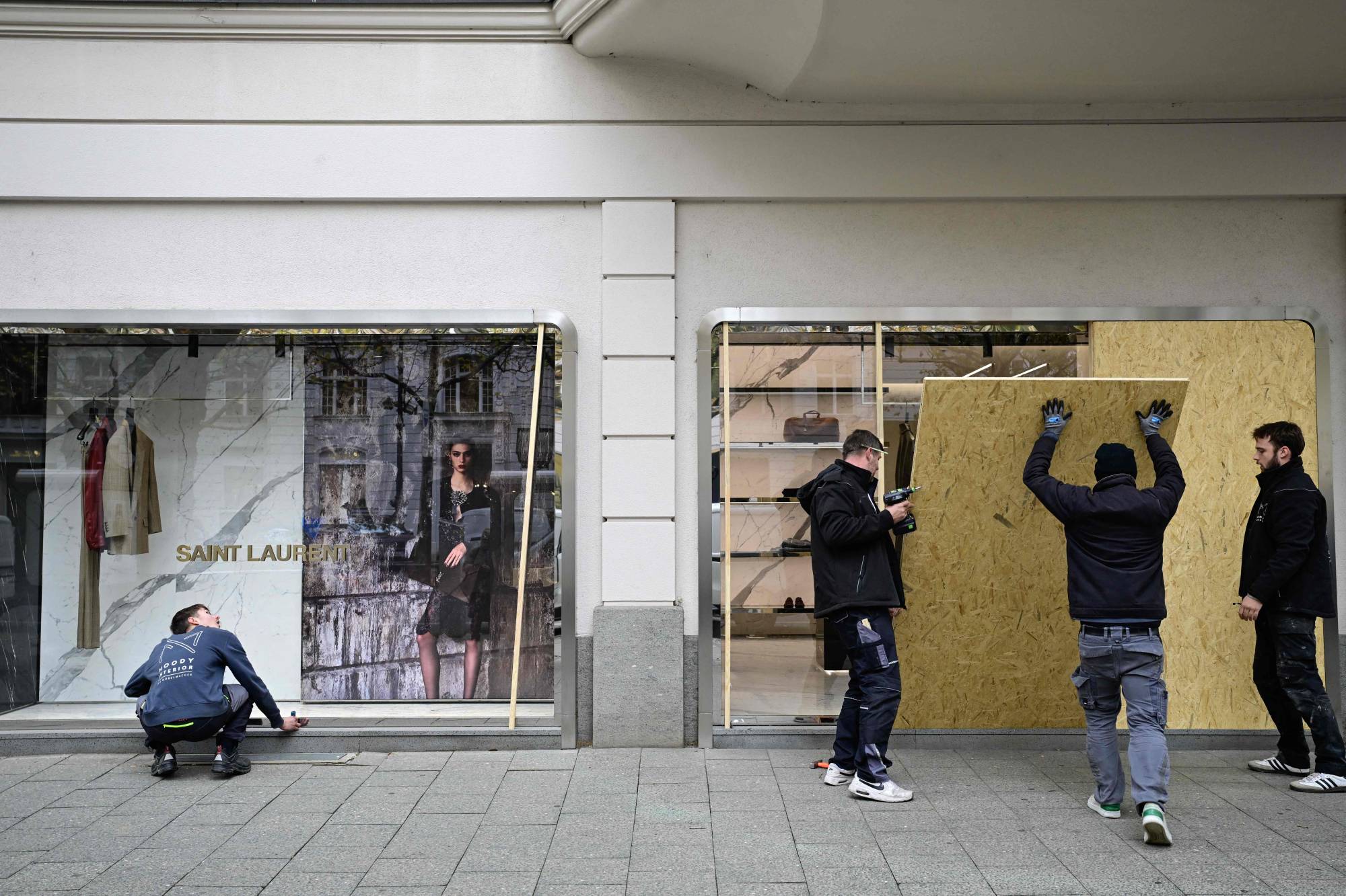 Berlin'de bir lüks giyim mağazasının çalışanları, olası olaylara karşı mağazanın önünü korumaya alıyor. (AFP)