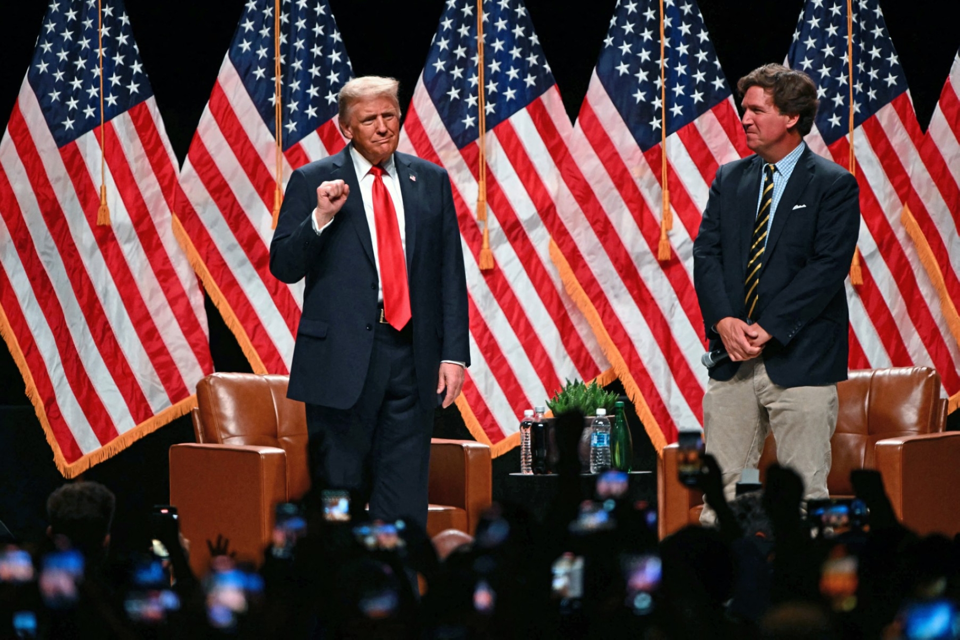 ABD Başkanı Donald Trump (solda), Arizona'daki canlı yayın turu sırasında Amerikalı yorumcu Tucker Carlson’a canlı bir röportaj vereceği yere geliyor, 31 Ekim 2024 (AFP)