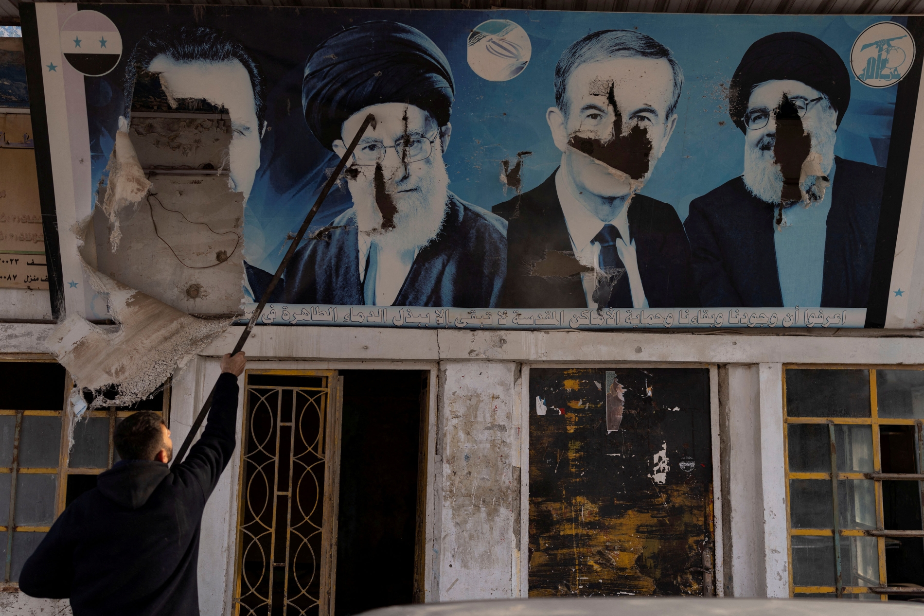 Suriye'nin Halep kırsalındaki Şii köyü Nubl'da bir benzin istasyonunda çekilen fotoğrafta, eski Cumhurbaşkanları Hafız ve Beşşar Esed ile eski Hizbullah Genel Sekreteri Hasan Nasrallah ve İran'ın eski Dini Lideri Ali Hamaney’i bir arada gösteren yırtılmış bir afişi görülüyor, 11 Aralık 2024 (Reuters)