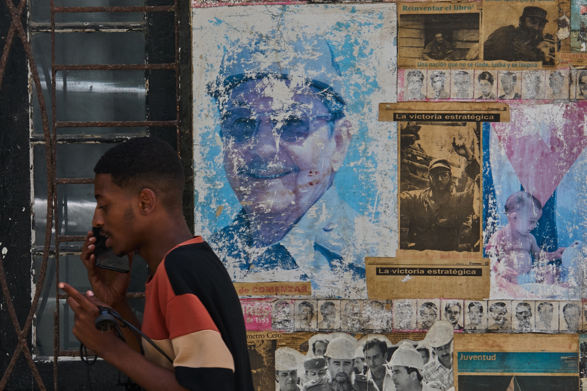 Havana'da Küba Devrimi hakkında bir sergide, duvardaki Raúl ve Fidel Castro fotoğraflarının yanında bir adam telefonla konuşuyor, 20 Mayıs 2026 (Associated Press)
