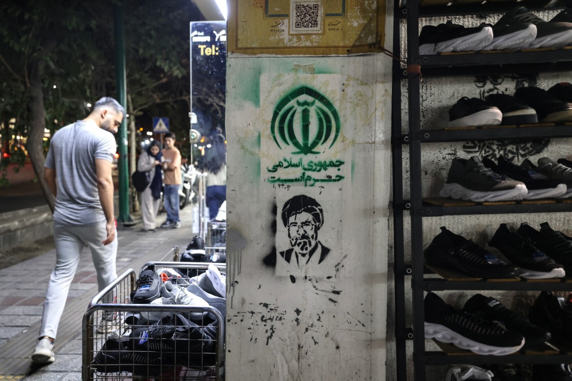 15 Eylül 2026'da Tahran'ın güneyinde, İran'ın “Yol Göstericisi” Mehtuba Hamaney'i tasvir eden bir grafiti resminin önünde yürüyen bir adam (AFP)