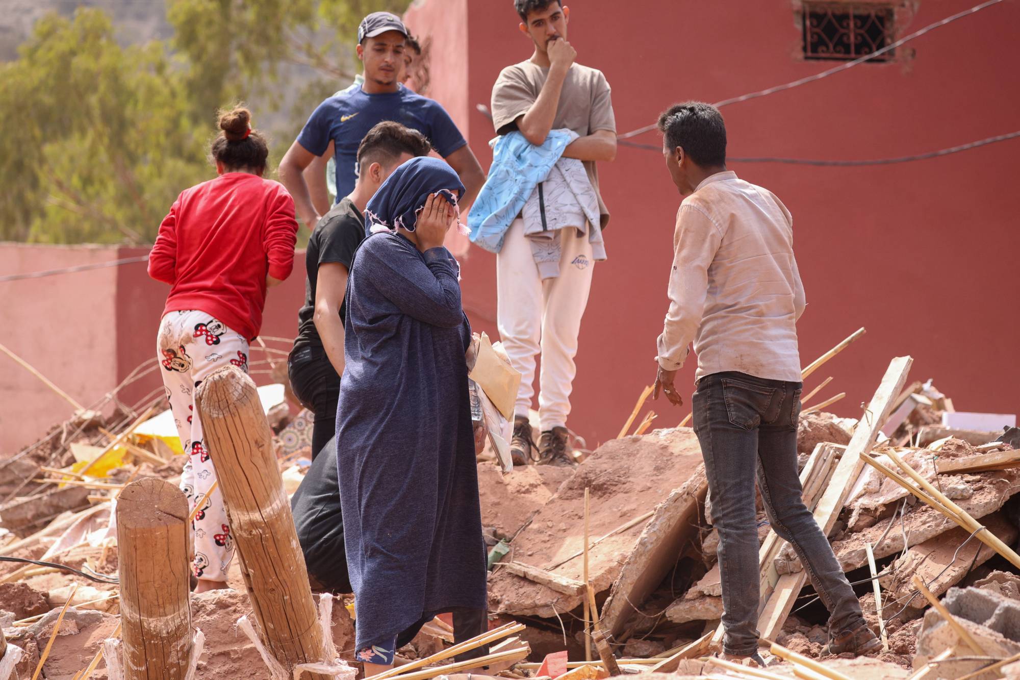 Fotoğraf altı: 12 Eylül 2023’te Fas’ın Ouirgane bölgesinde depremzede bir kişinin yakınları enkazın üzerinde beklerken (EPA)