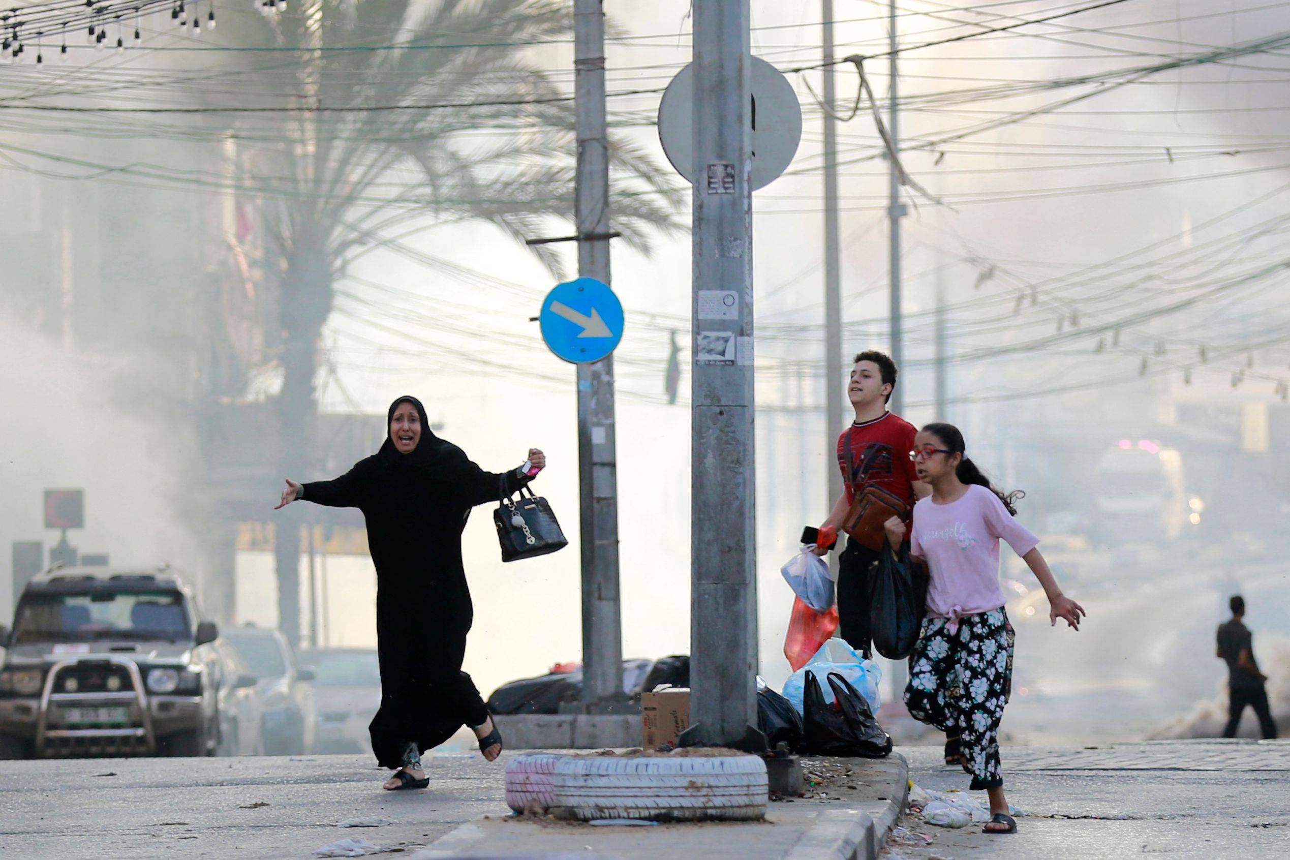 FOTO: İsrail'in Gazze Şehri'ndeki Şifa Hastanesi yakınlarına düzenlediği saldırının ardından korunaklı bir bölgeye kaçmaya çalışan Filistinliler. (AFP)