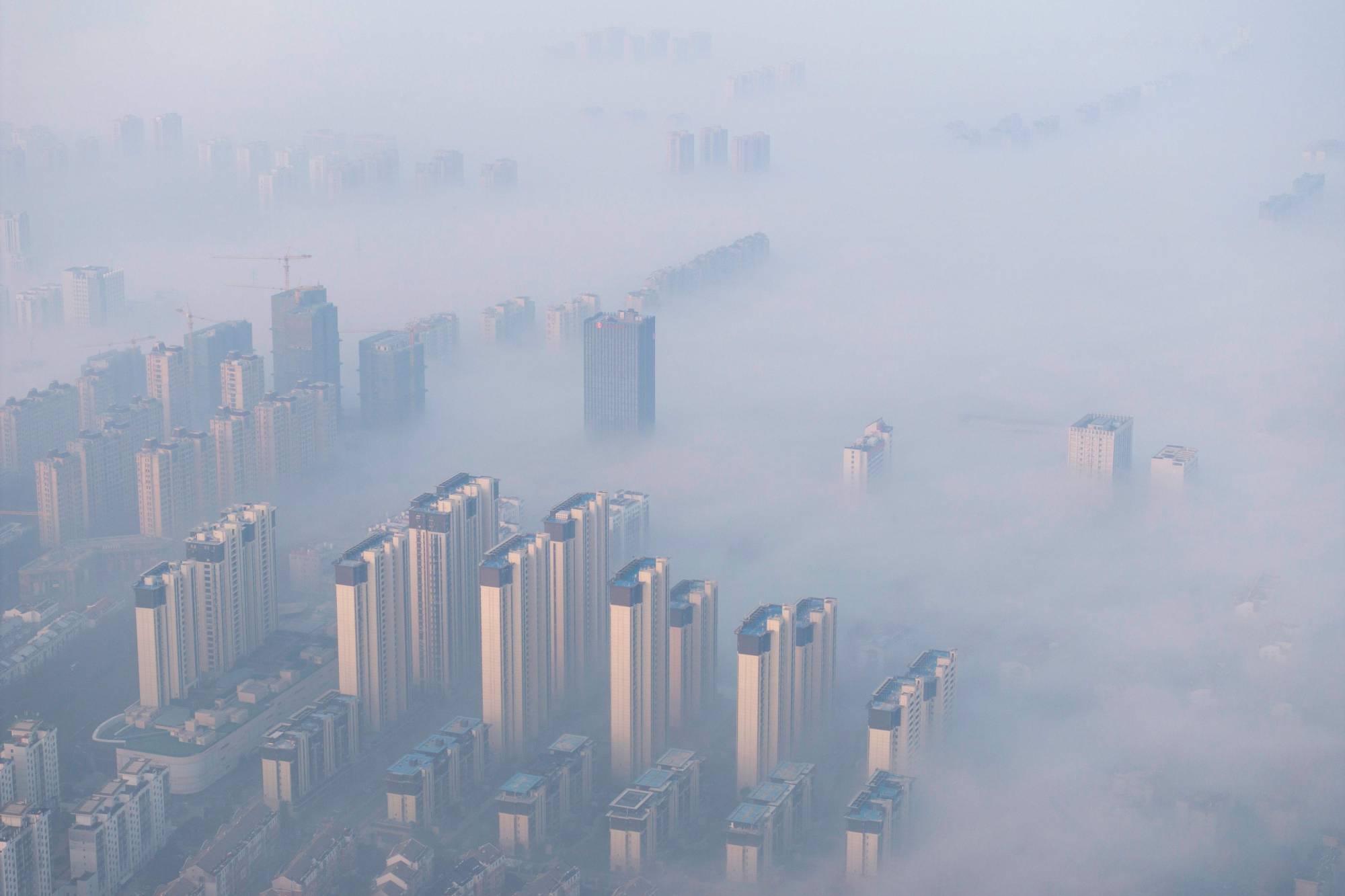 Fotoğraf Altı: Çin'in doğusundaki Jiangsu eyaletindeki Huaian, sis ve hava kirliliğiyle kaplandı. (AFP)