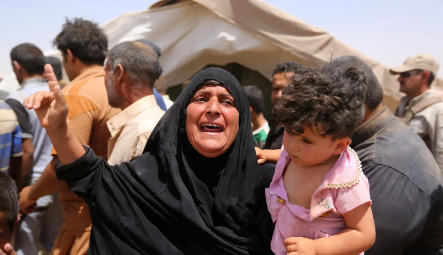 سيدة عراقية في حالة غضب عقب خروجها من منزلها في الرمادي مع طفلها بسبب تمدد «داعش» إلى مخيم إغاثة في عامرية الفلوجة (أ.ب)