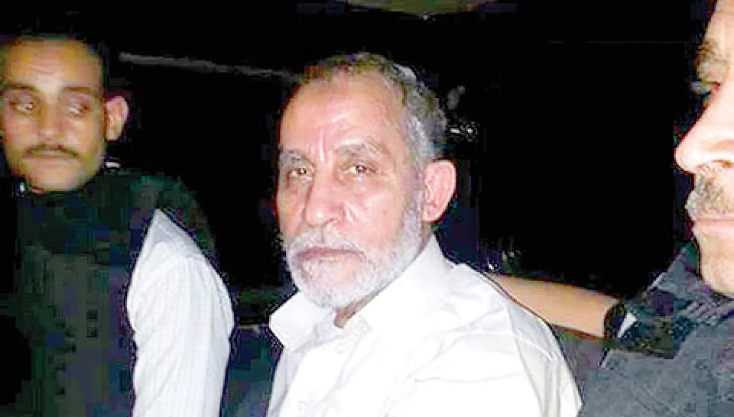 محمد بديع المرشد الأعلى للإخوان المسلمين بمصر يتوسط عنصرين من قوات الأمن أثناء القبض عليه أمس (أ.ف.ب)