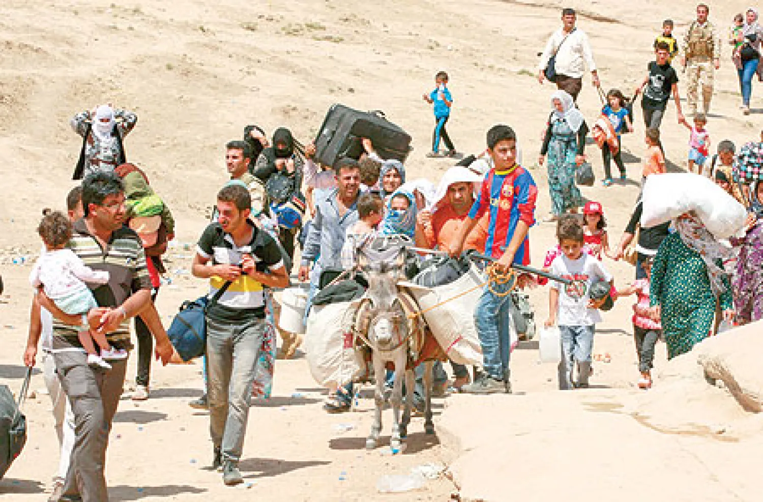 لاجئون سوريون أكراد يعبرون الحدود السورية متجهين نحو العراق أمس (أ.ب)