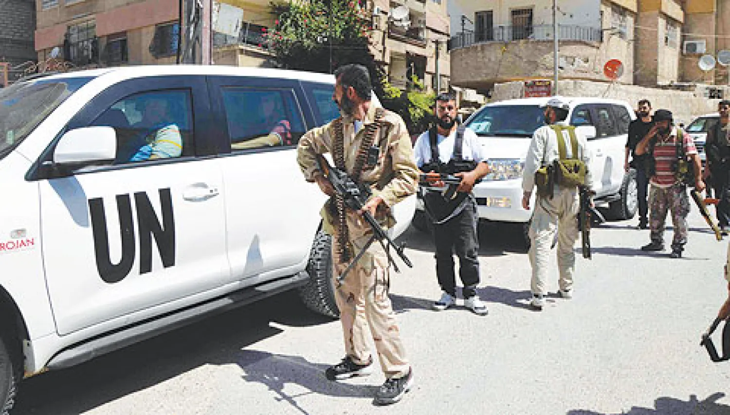 مقاتلون من الجيش السوري الحر يقومون بحماية فريق التفتيش الاممي في زملكا قرب دمشق أمس (رويترز)