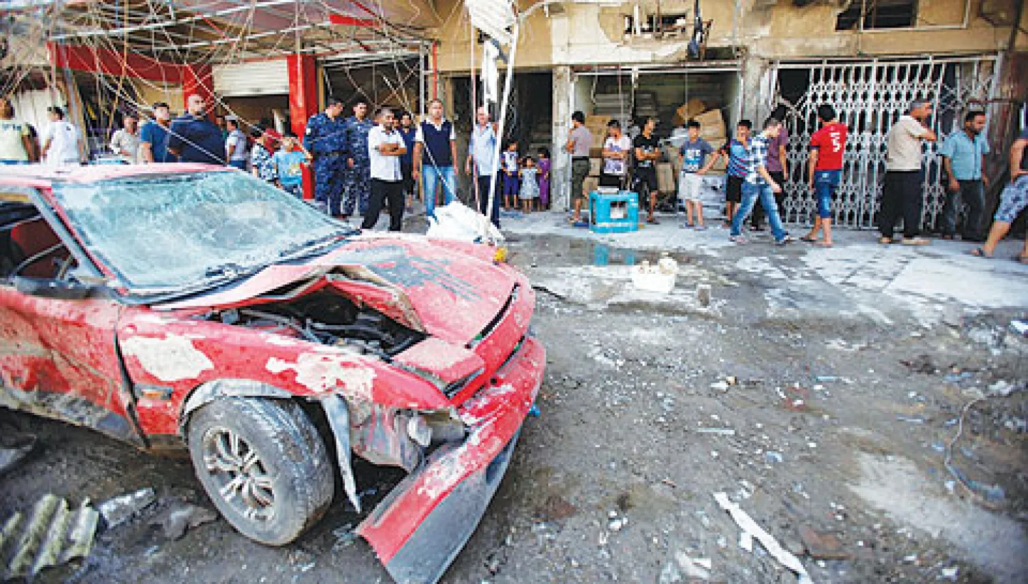 عراقيون يتجمعون في مكان انفجار سيارة مفخخة بمنطقة الشعب ببغداد أمس (رويترز)