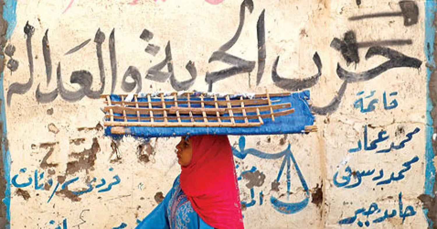 سيدة تمر أمام شعار لحزب الحرية والعدالة التابع لجماعة الإخوان في وسط القاهرة أمس (رويترز)