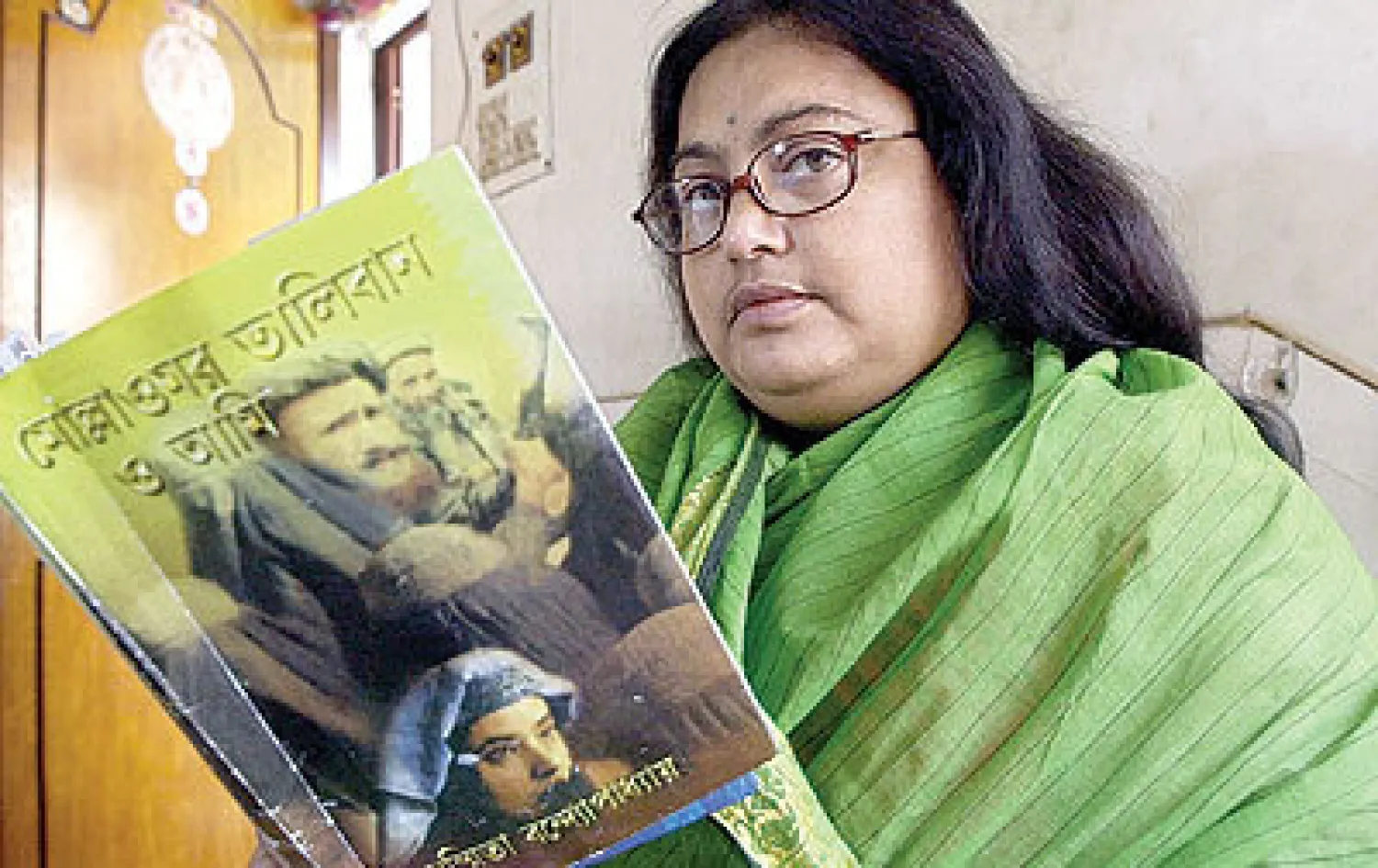 سوشميتا بانرجي تحمل واحدة من رواياتها باللغة البنغالية بعنوان «الملا عمر، طالبان وأنا» في كولكاتا في 2003 (أ.ف.ب)