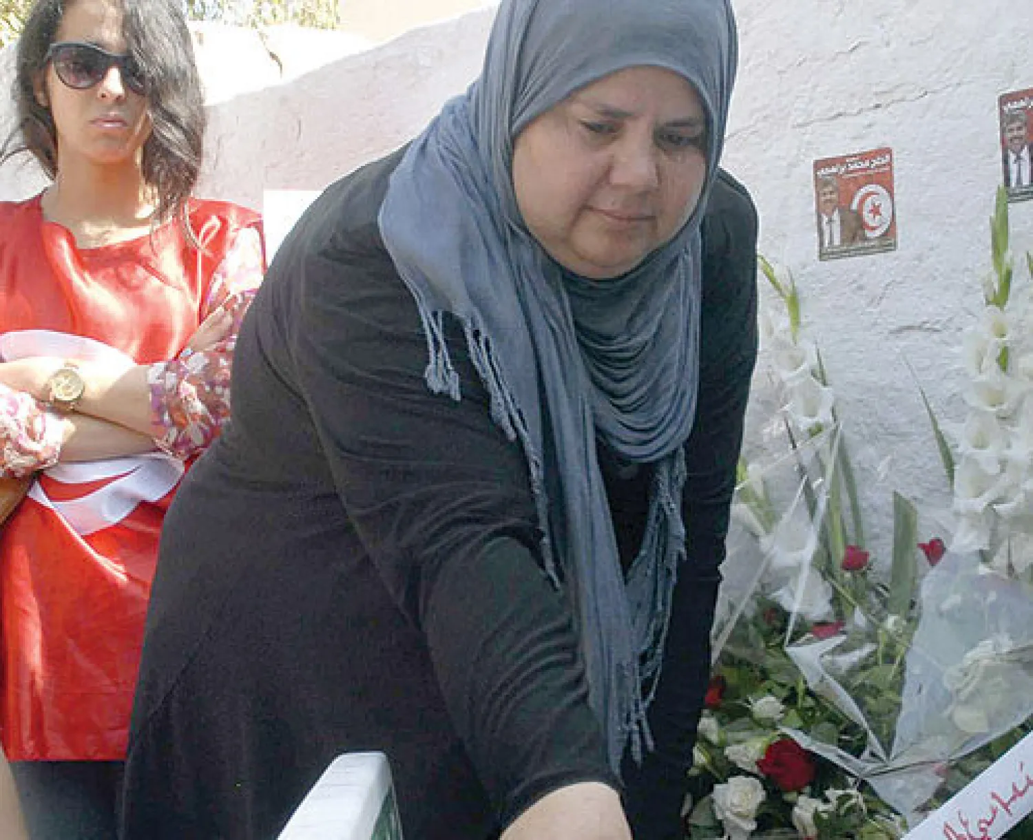 أرملة السياسي التونسي المعارض المغتال محمد البراهمي تضع وردة على قبره بمناسبة ذكرى أربعينيته في تونس أمس (أ.ف.ب)