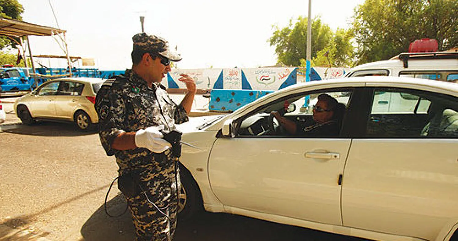 شرطي عراقي يوقف سيارة عند نقطة تفتيش في شارع أبو نواس ببغداد (رويترز)