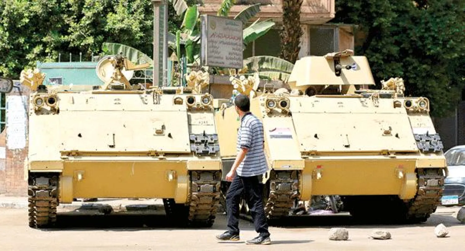 شاب مصري يعبر أمام مدرعتين تابعتين للجيش في وسط القاهرة اليوم (أ.ب)