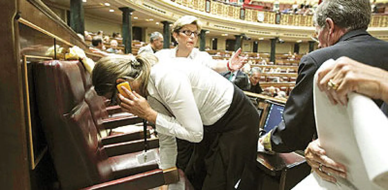 أعضاء في البرلمان يقومون بتجفيف مقاعدهم بعد تسريبات المياه من السقف (إ.ب.أ)