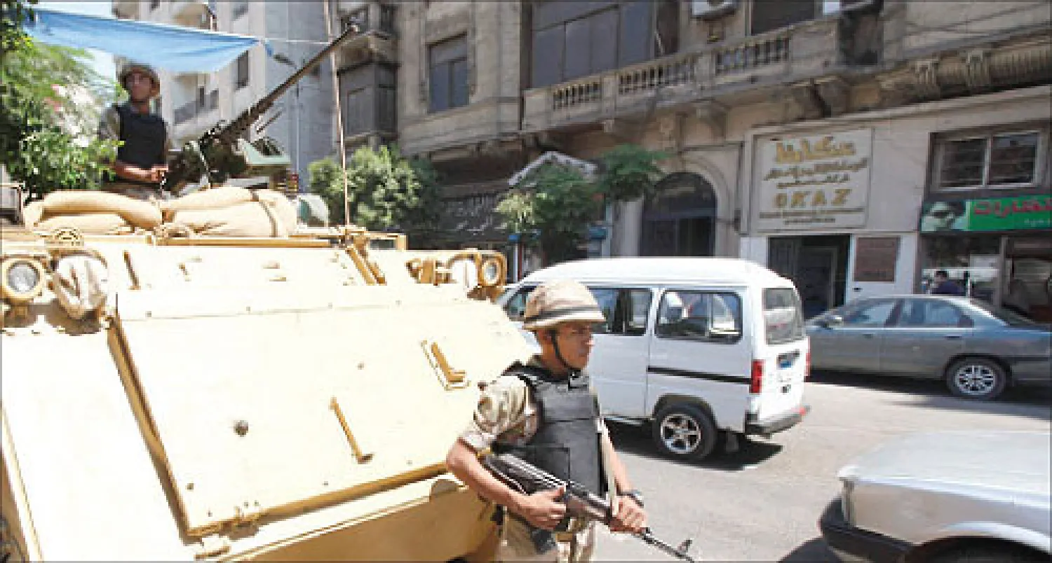 جندي في نوبة حراسة أمام عربة مدرعة بالقرب من مسجد الفتح في ميدان رمسيس بوسط القاهرة أمس (رويترز)