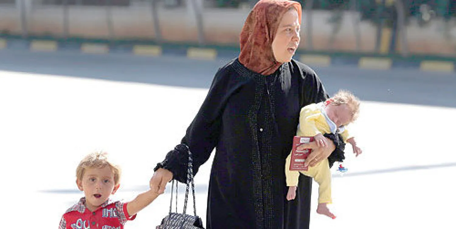 عائلة سورية تجتاز منطقة باب الهوى الحدودية متجهة نحو تركيا للالتحاق بمخيمات اللاجئين هناك (إ.ب.أ)