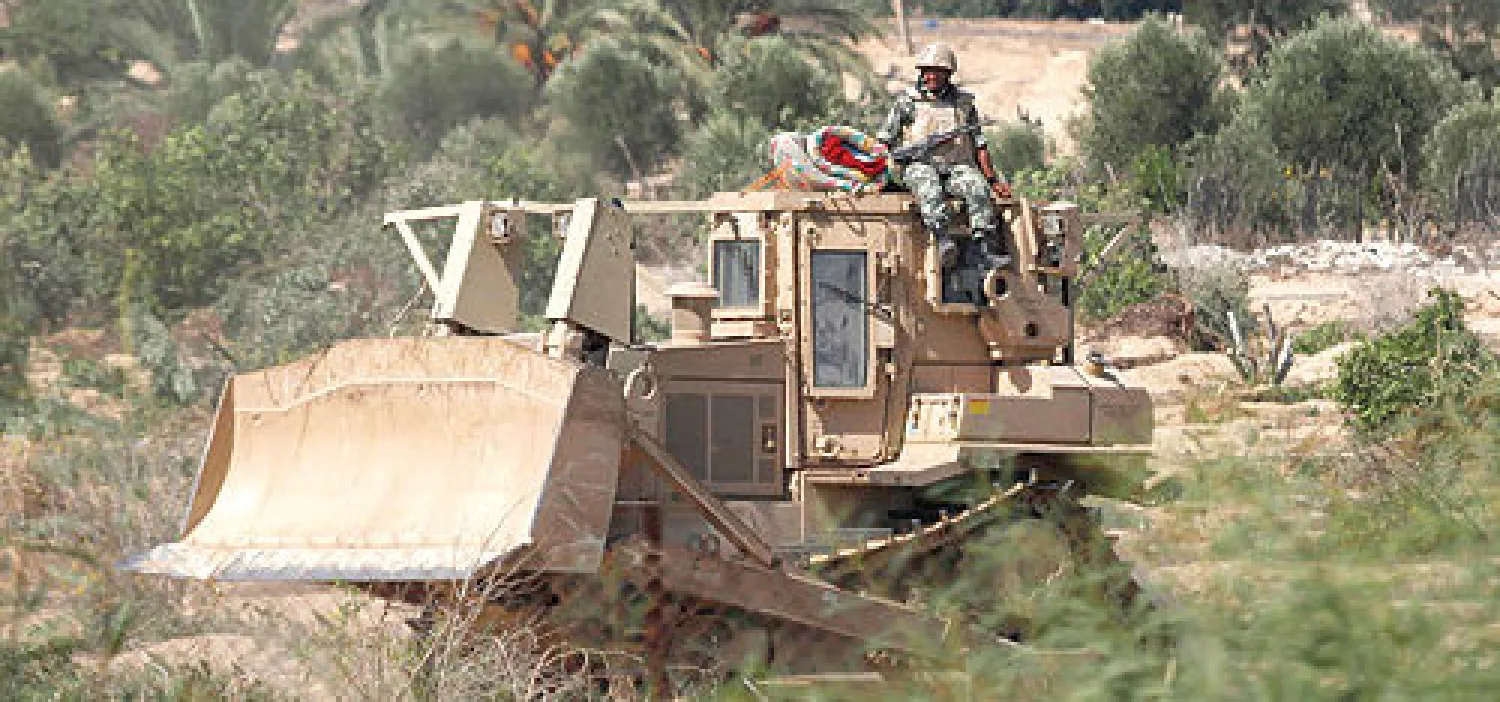 جندي مصري في نوبة مراقبة وحراسة أمس من فوق إحدى الجرافات المشاركة في العمليات الأمنية في شمال سيناء (رويتز)