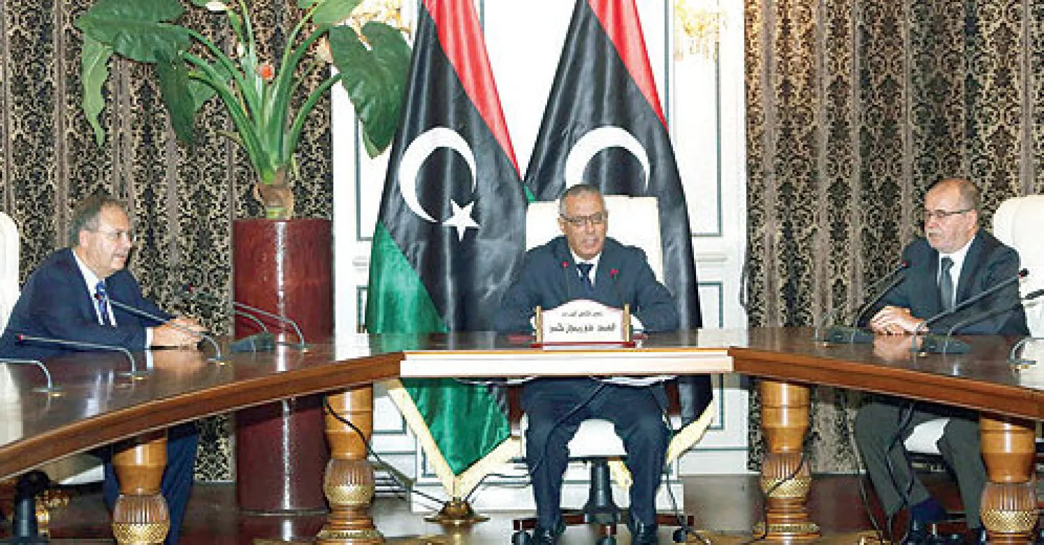 رئيس الحكومة الليبية علي زيدان يتوسط طارق متري رئيس بعثة الأمم المتحدة للدعم في ليبيا (يسار) ونائب رئيس المجلس الوطني الليبي جمعة عتيقه لدى حضورهم مؤتمراً صحافياً في طرابلس (أ.ف.ب)