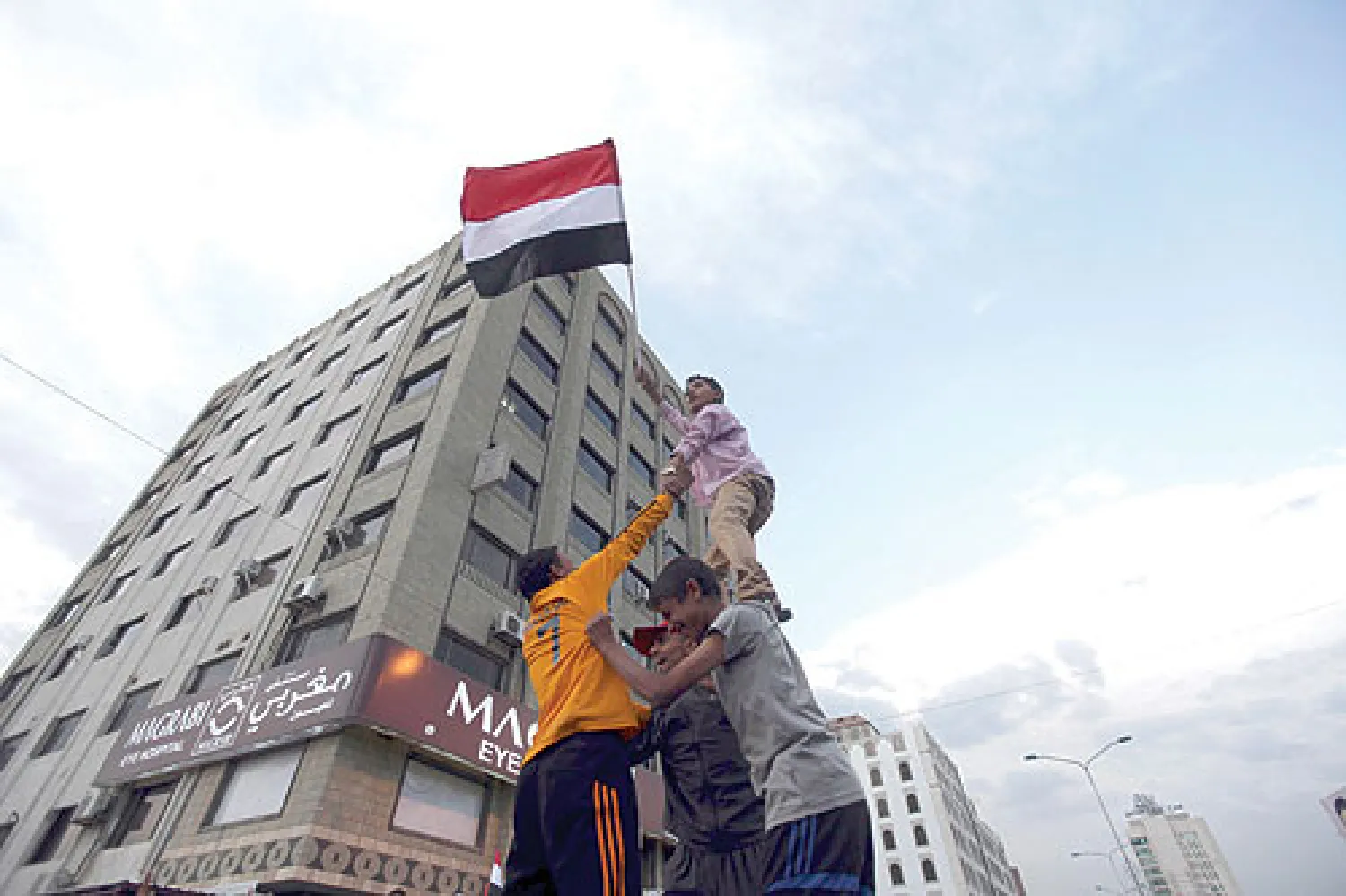 يمنيون يرفعون علم بلادهم خلال مظاهرة في صنعاء أمس (رويترز)