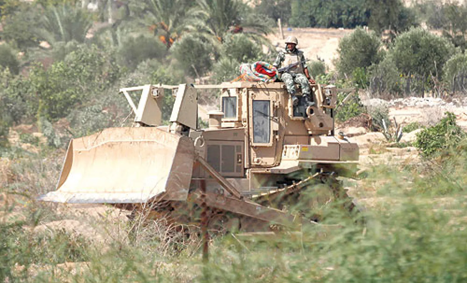 جندي مصري يراقب من أعلى بلدوزر تابع للجيش الشريط الفاصل بين الأراضي المصرية وقطاع غزة (رويترز)